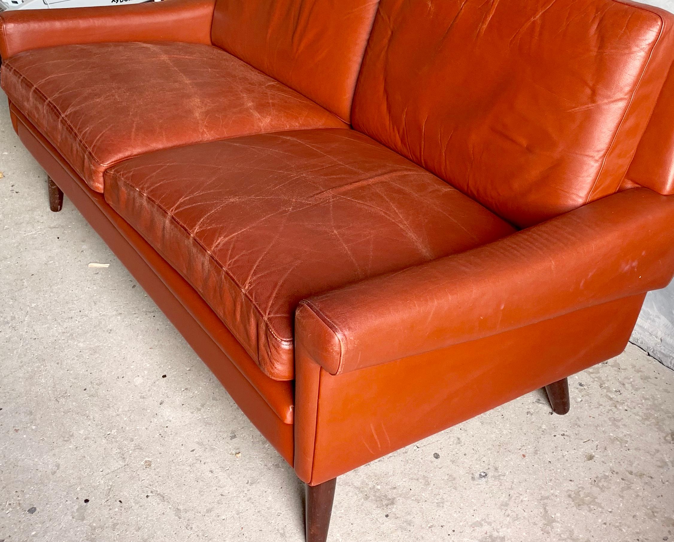 Beautiful Svend skipper sofa designed and produced in Denmark. Covered with red leather, with round tapered legs.