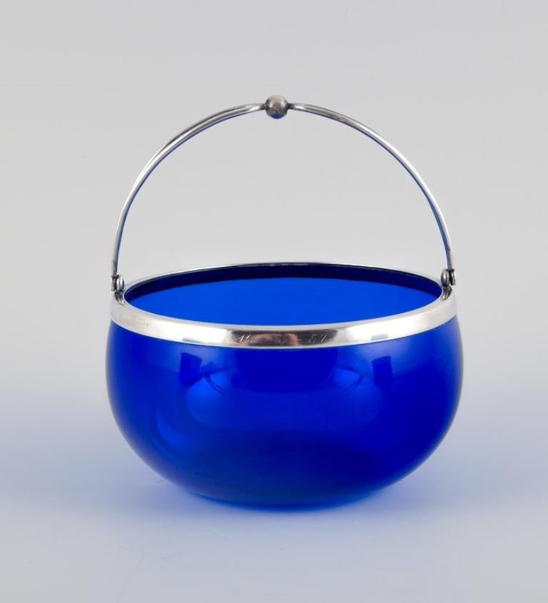 Svend Toxværd, Danish silversmith. 
Sugar bowl in blue art glass and Danish 830 silver.
Mid-20th century.
In excellent condition.
Engraving in the silver.
Marked.
Dimensions: Height without handle 5.5 cm. x diameter 10.5 cm.
