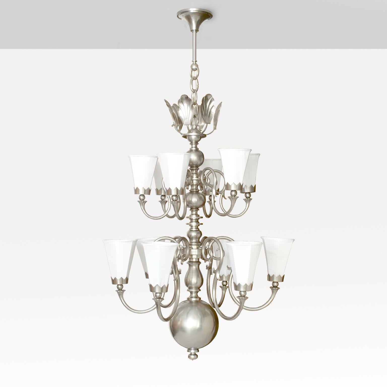 Large 1920's Scandinavian Modern 12-arm chandelier, brass with nickel plate finish. Each arm has a fabric covered 6-sided shade held in place with a crown shaped bobeche. The third-tier is a cluster of stylized shells which reflect light when the