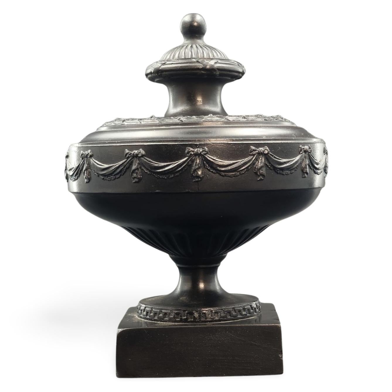 Un jarrón especialmente logrado en basalto negro, con una deocración sencilla y clásica, o con guirnaldas y bayas y hojas. Este jarrón pertenece al periodo de Wedgwood & Bentley, durante el cual la empresa produjo la mayoría de sus mejores obras.