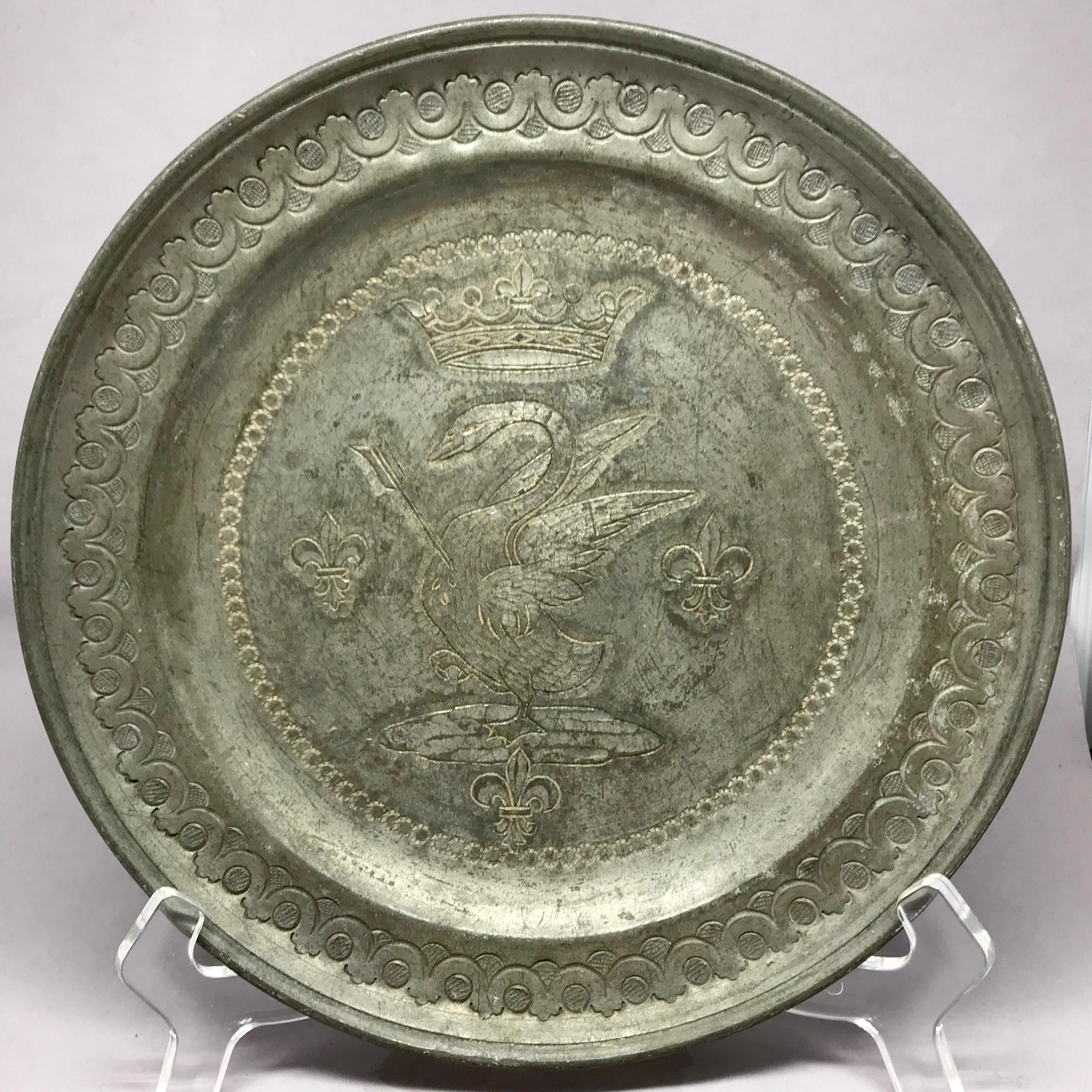 Swan Pewter plate. Elegant 9' stamped and chased pewter dish with guilloche border centering a crowned and impaled swan flanked by three fleur-de-lis and further impressed bead banding. Markings for 