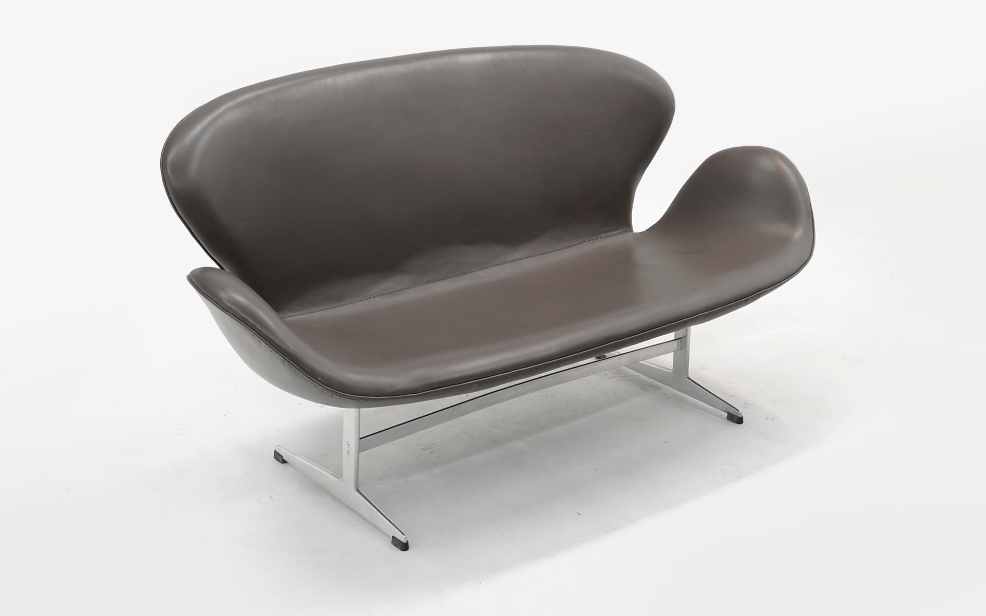 Rare et ancien canapé / siège d'amour Arne Jacobsen en cuir taupe / gris chaud d'origine. Pas de déchirures ni d'éraflures. Légère décoloration. Très bon état d'origine.