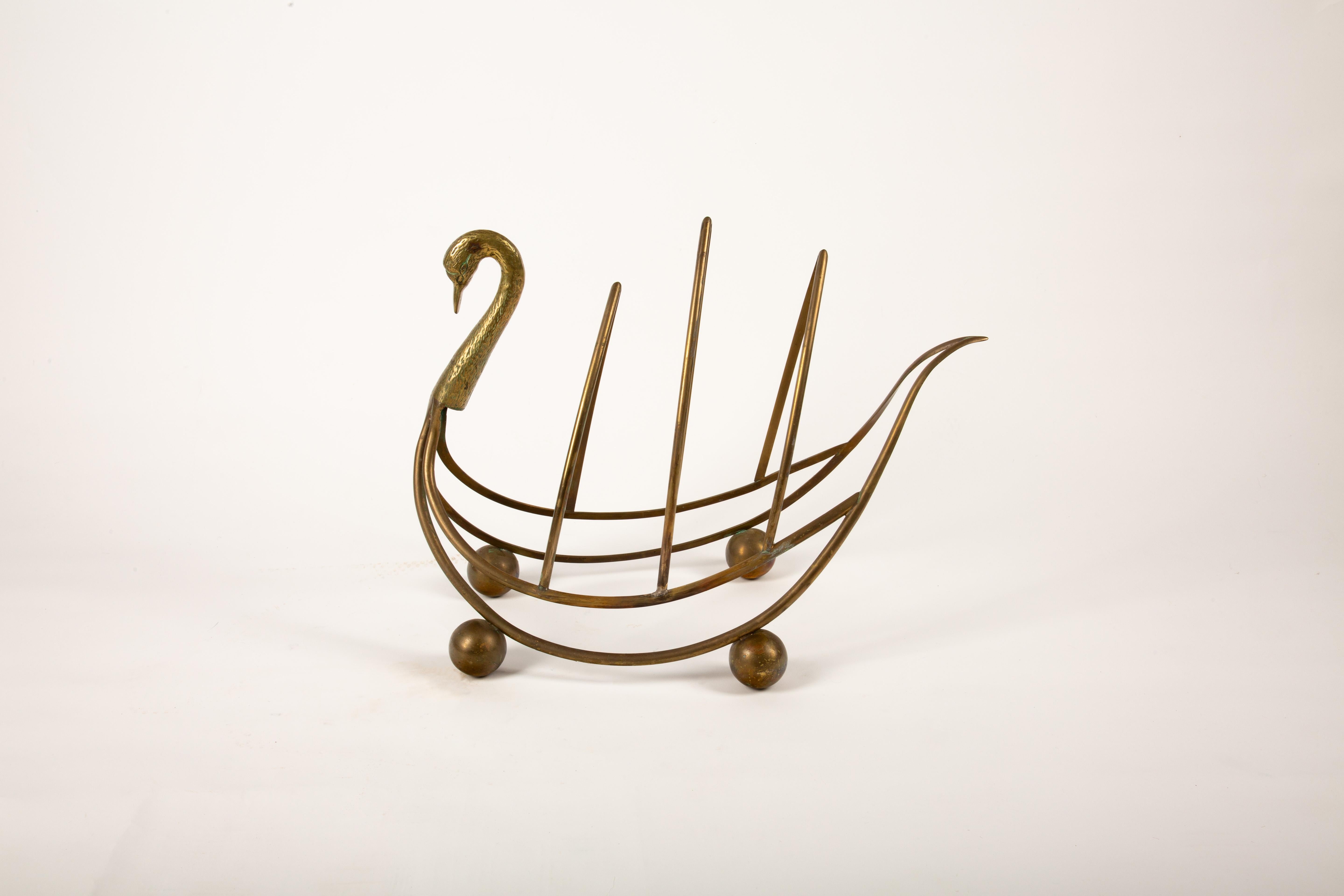 Un affascinante portariviste o portagiornali in ottone patinato della metà del secolo scorso, progettato con l'elegante forma di un cigno. La graziosa struttura è caratterizzata da un collo e una testa in ottone delicatamente dettagliati, che