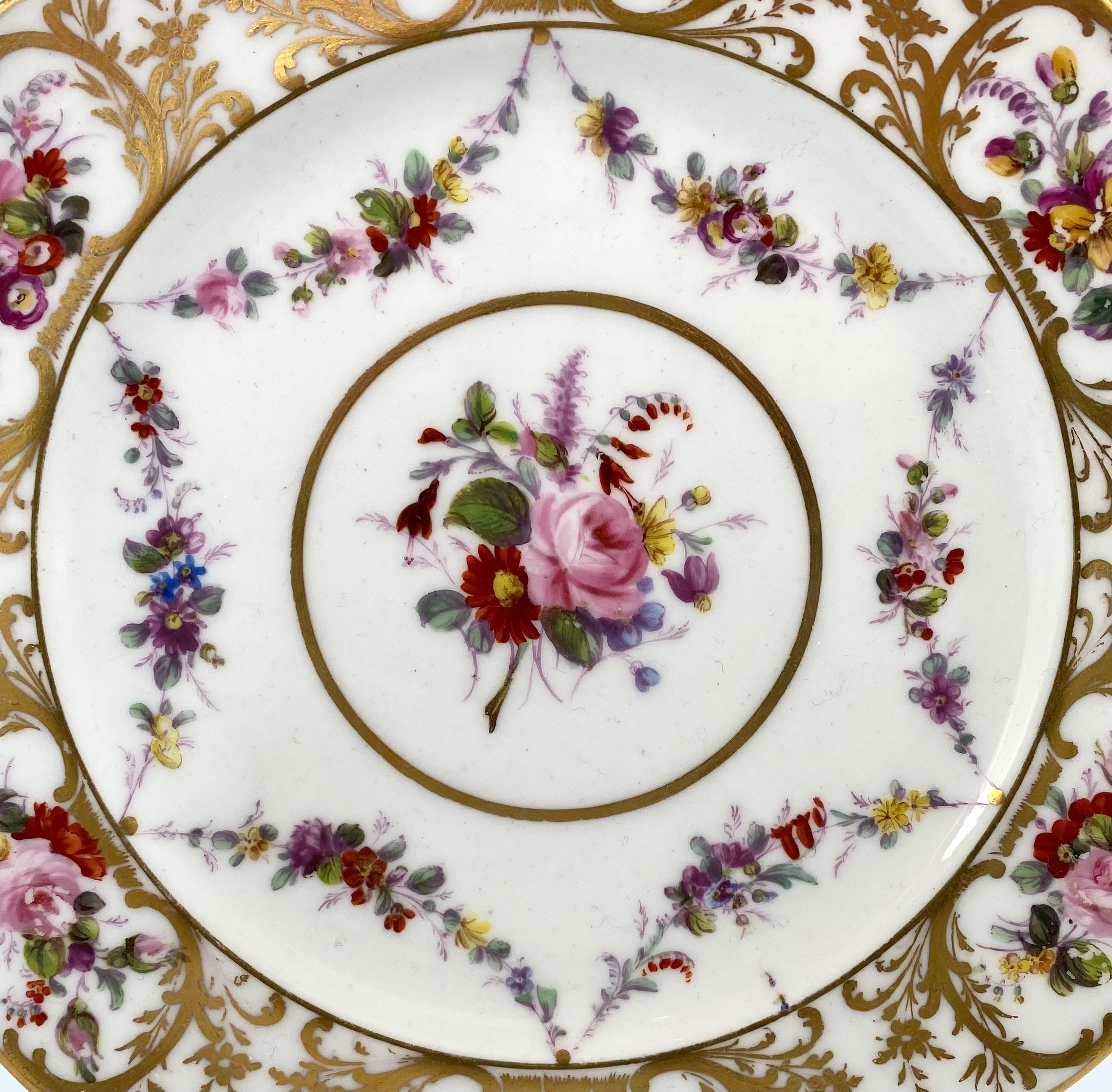 Swansea porcelain plate, c. 1815. The shaped plate, painted to the centre, with a spray of flowers, within a circular, gilt panel. Surrounded by swags of flowers.
The border with further gilt ‘C’ scroll panels of flowers, divided by gilt