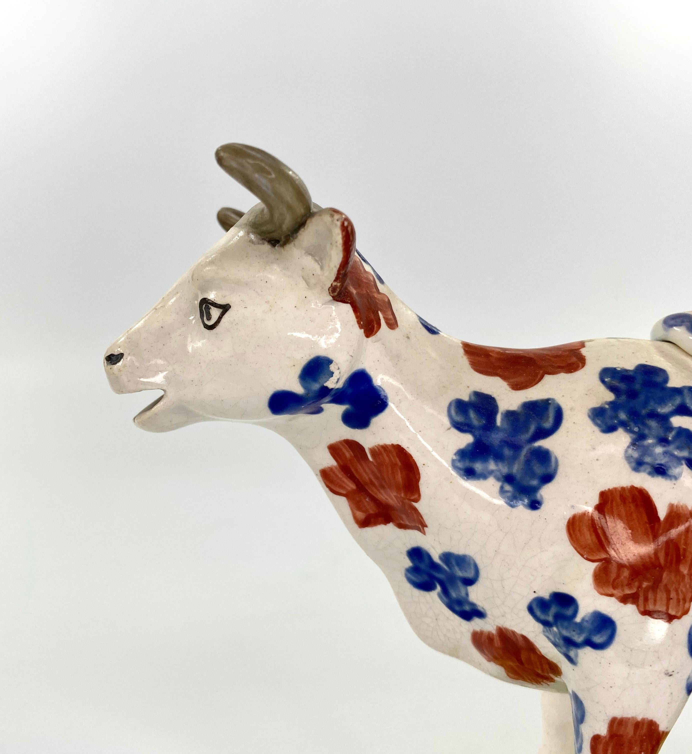 Swansea pottery Pearlware cow creamer, circa 1820. The typically modelled cow, painted with blue and red spots, and standing upon a moulded grassy mound base.
Having the original cover.
Medium: Earthenware
Measures: Height 14 cm, 5 1/2”.
Width