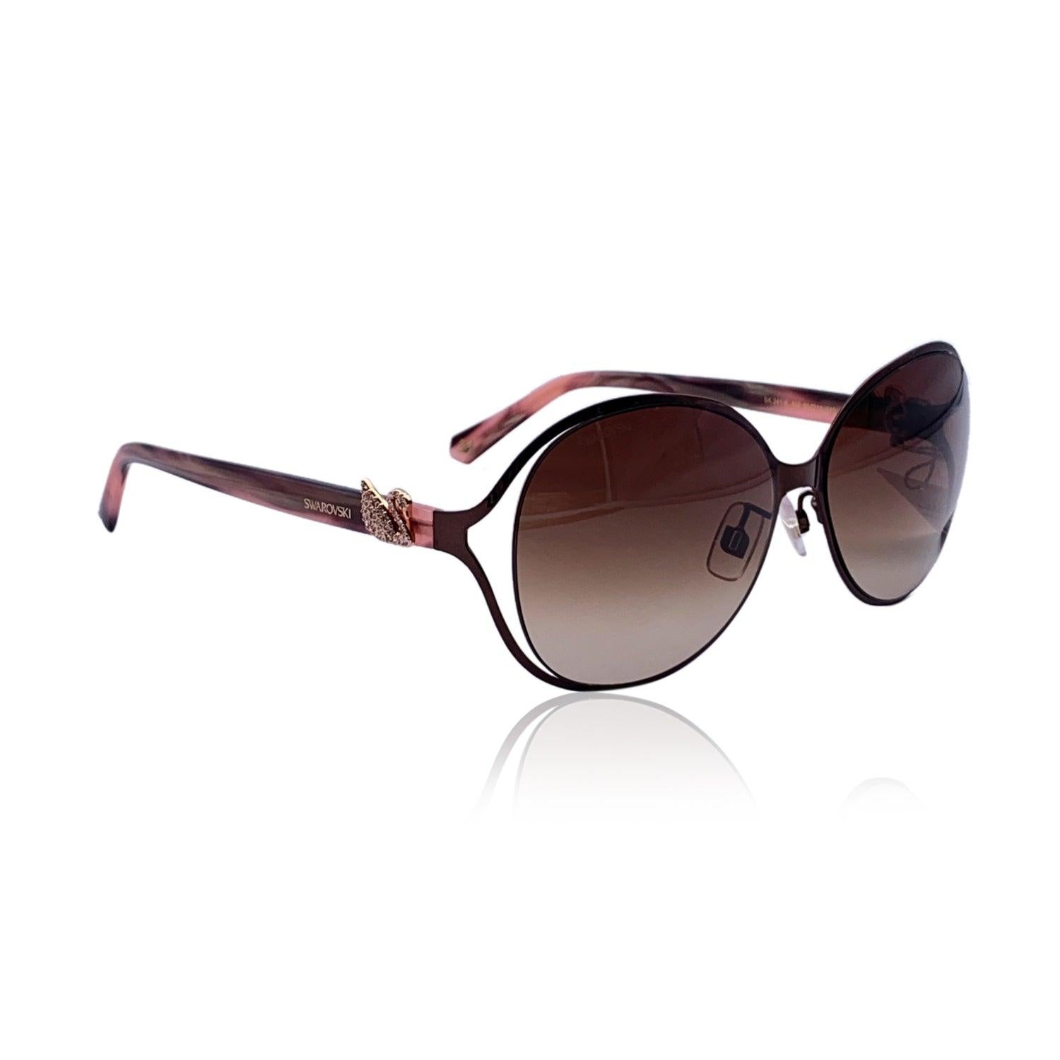 Swarovski sunglasses, Mod. SK 241-K. Brown metal frame with pink marbled acetate ear stems. Pink crystal swans on the temples. Original 100% Total UVA/UVB protection lenses in gradient brown color. Ref & Numbers: 241-K 45F - 60/15 140 - 3. Imported