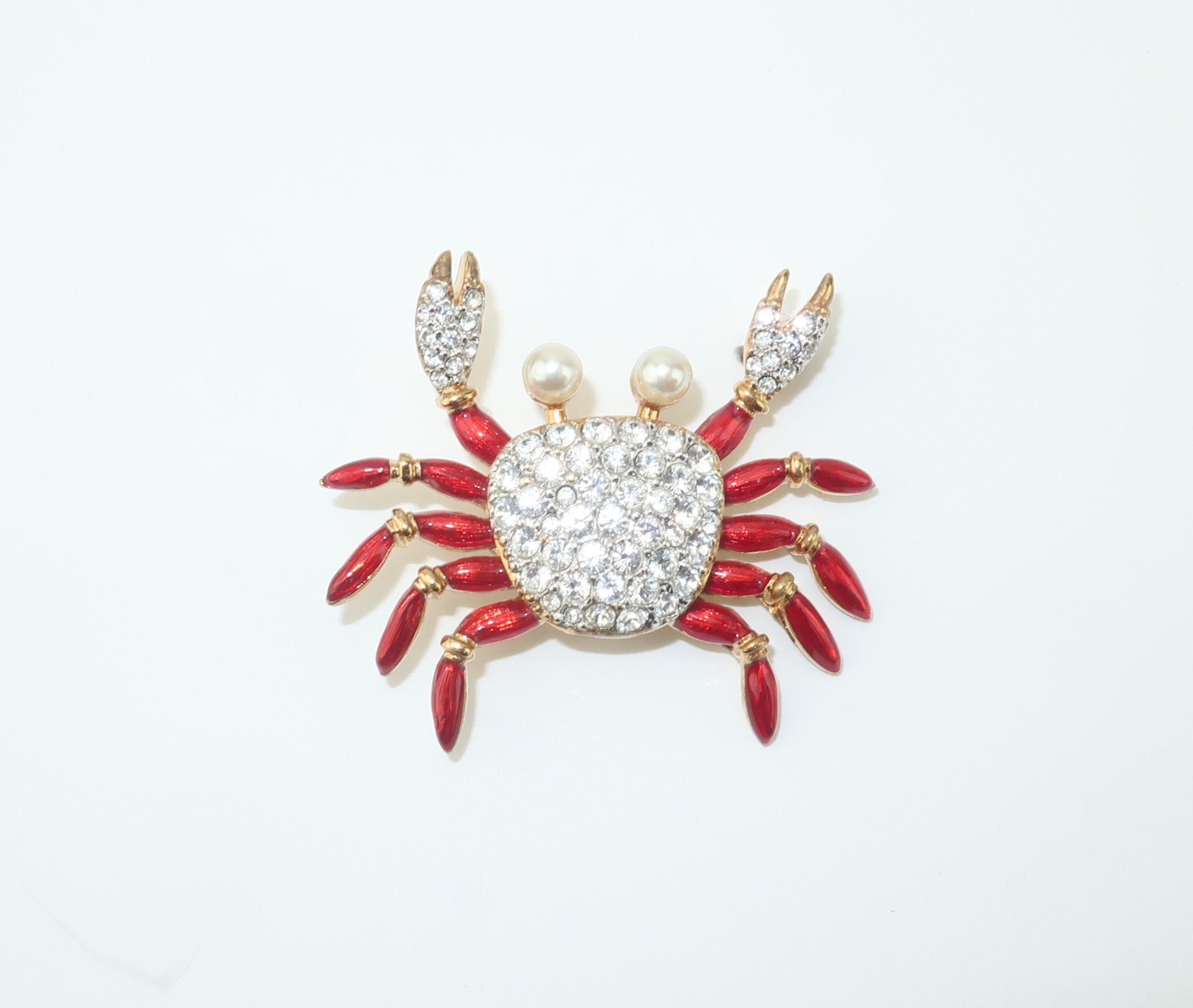 An adorable Swarovski crab brooch loaded with personality and adorned with brilliant crystals, red enamel and faux pearls.  Set in a gold tone metal and outfitted with a straight pin and safety catch.  Signed with the Swarovski iconic swan logo. 