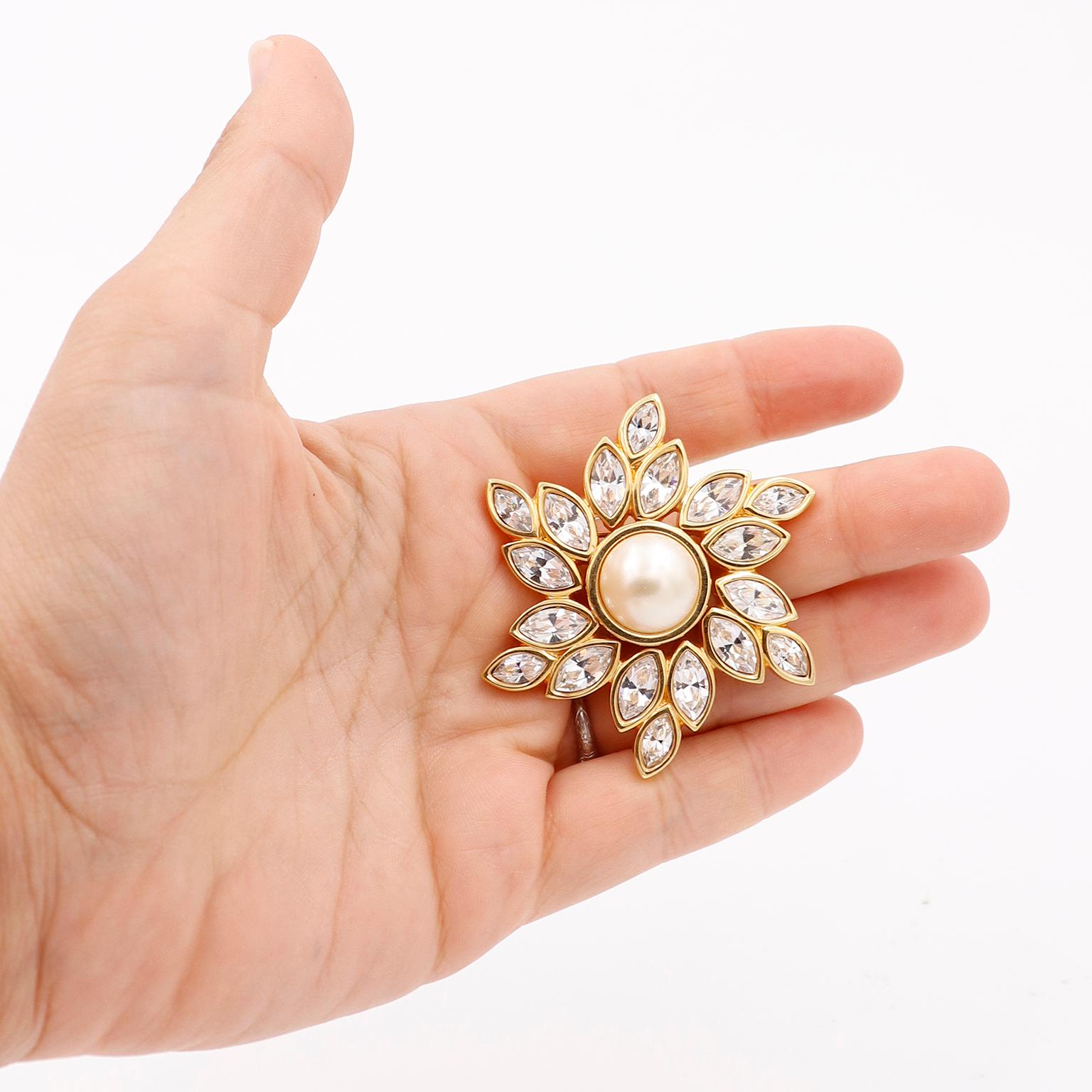 This gorgeous gold plated Swarovski crystal brooch is a star shaped flower with a faux pearl center. The brooch is marked with the Swarovski 