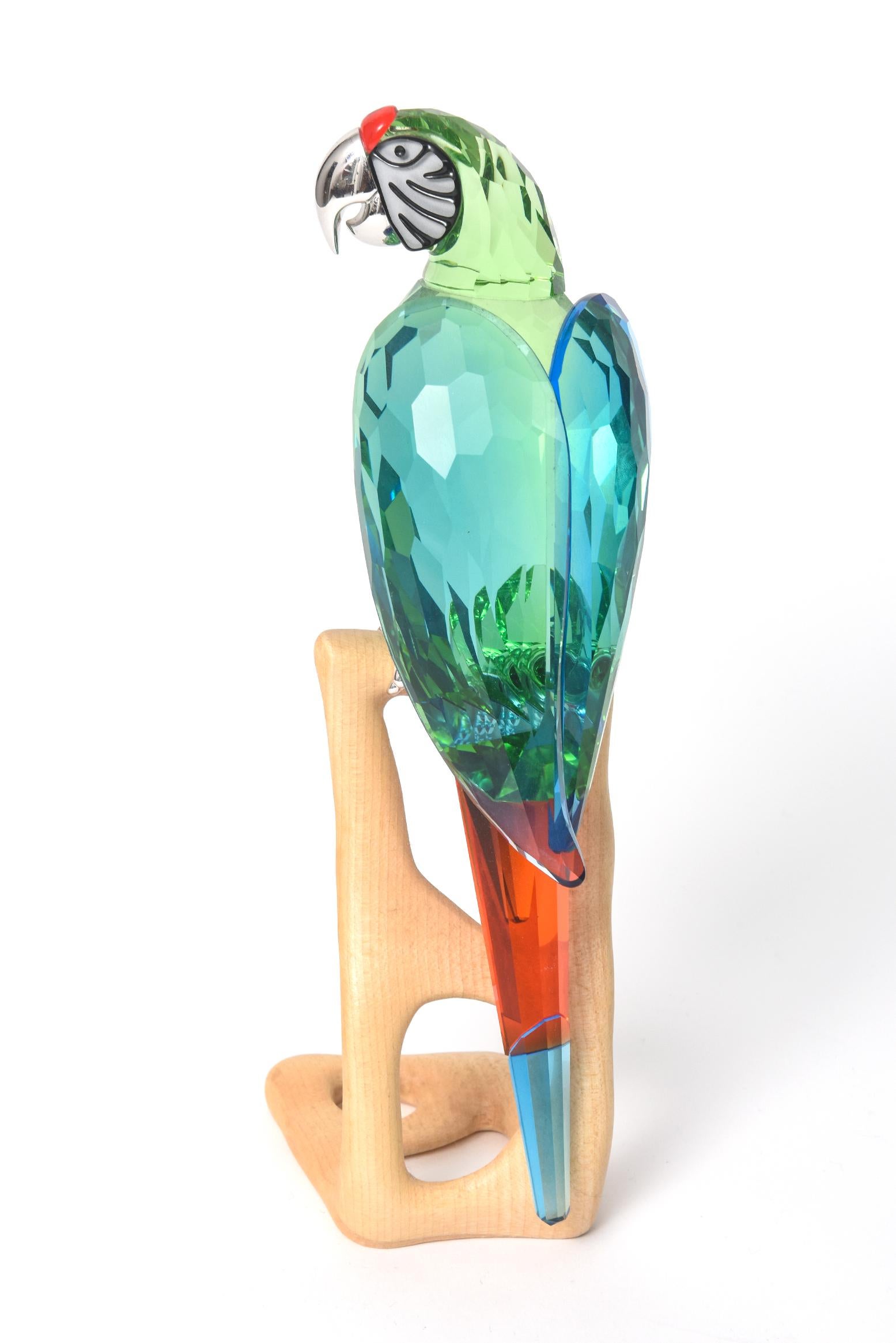 Un magnifique ara en cristal Swarovski de 9,25 pouces de haut, vert chrome, #685824 est livré avec sa boîte d'origine et ses papiers. Cet oiseau du Paradis est en cristal vert et son bec est en métal chromé. L'ara est posé sur un socle en bois.