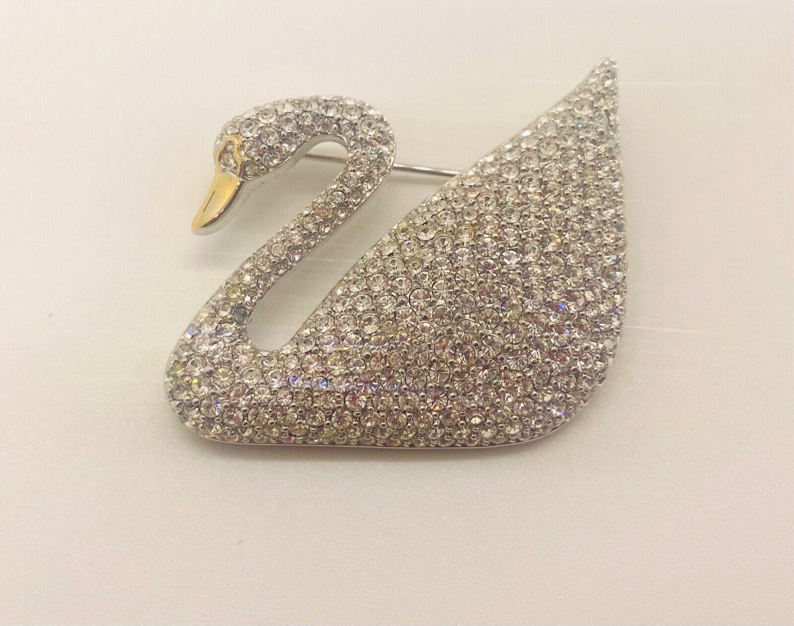 A beautiful authentic Swarovski Swan shaped brooch or pin engraved with the Swarovski logo and 1895-1995. 
The silver tone pin/ brooch is entirely done with clear colored paddle small crystals and looks and is finely handcrafted. The brooch comes