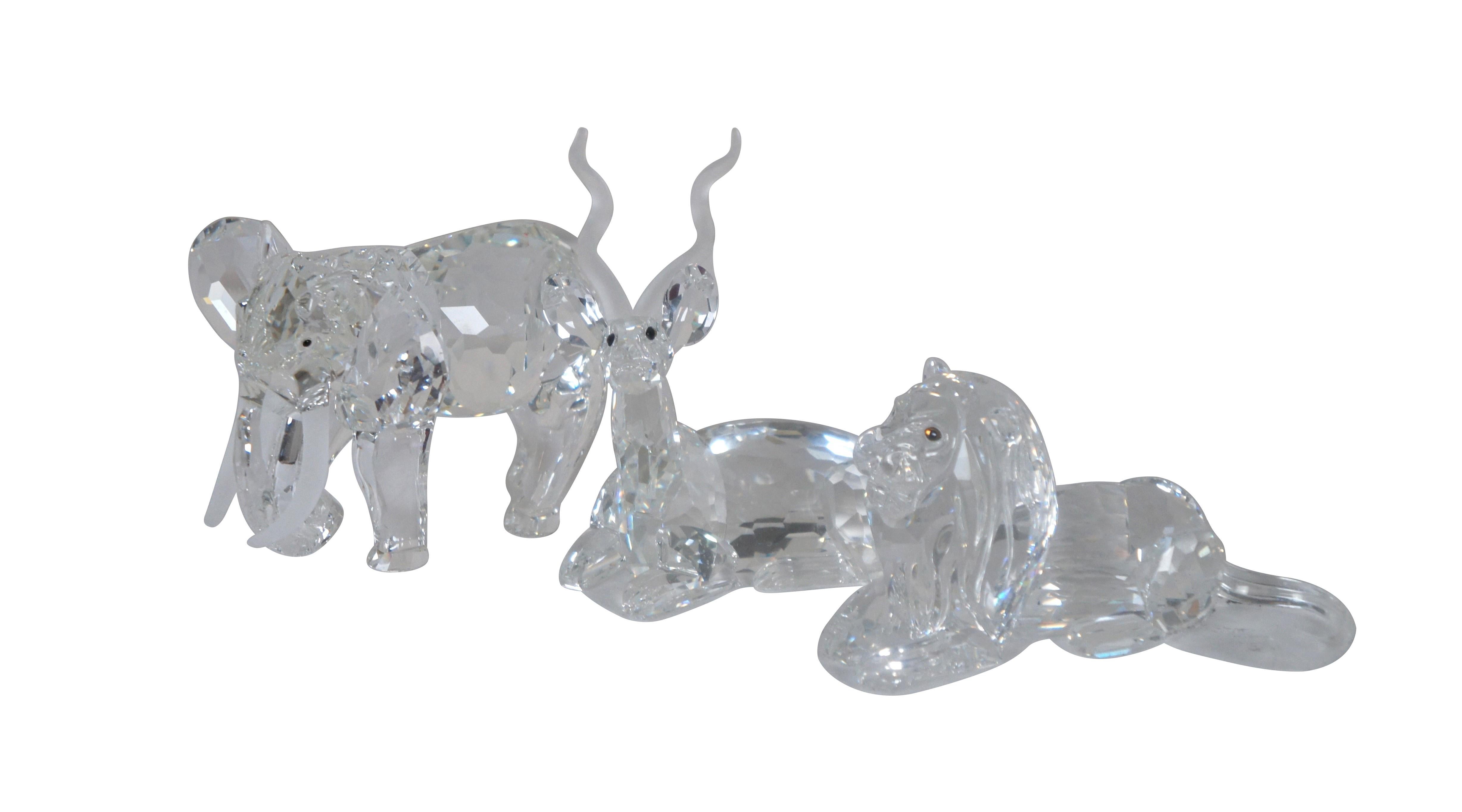 Swarovski Collectors Society Annual Edition Inspiration Africa taxidermy series trilogy including 1993 - The Elephant, 1994 - The Kudu, and 1995 - The Lion. Clear crystal figurines with frosted accents and dark amber eyes. Includes Certificates of