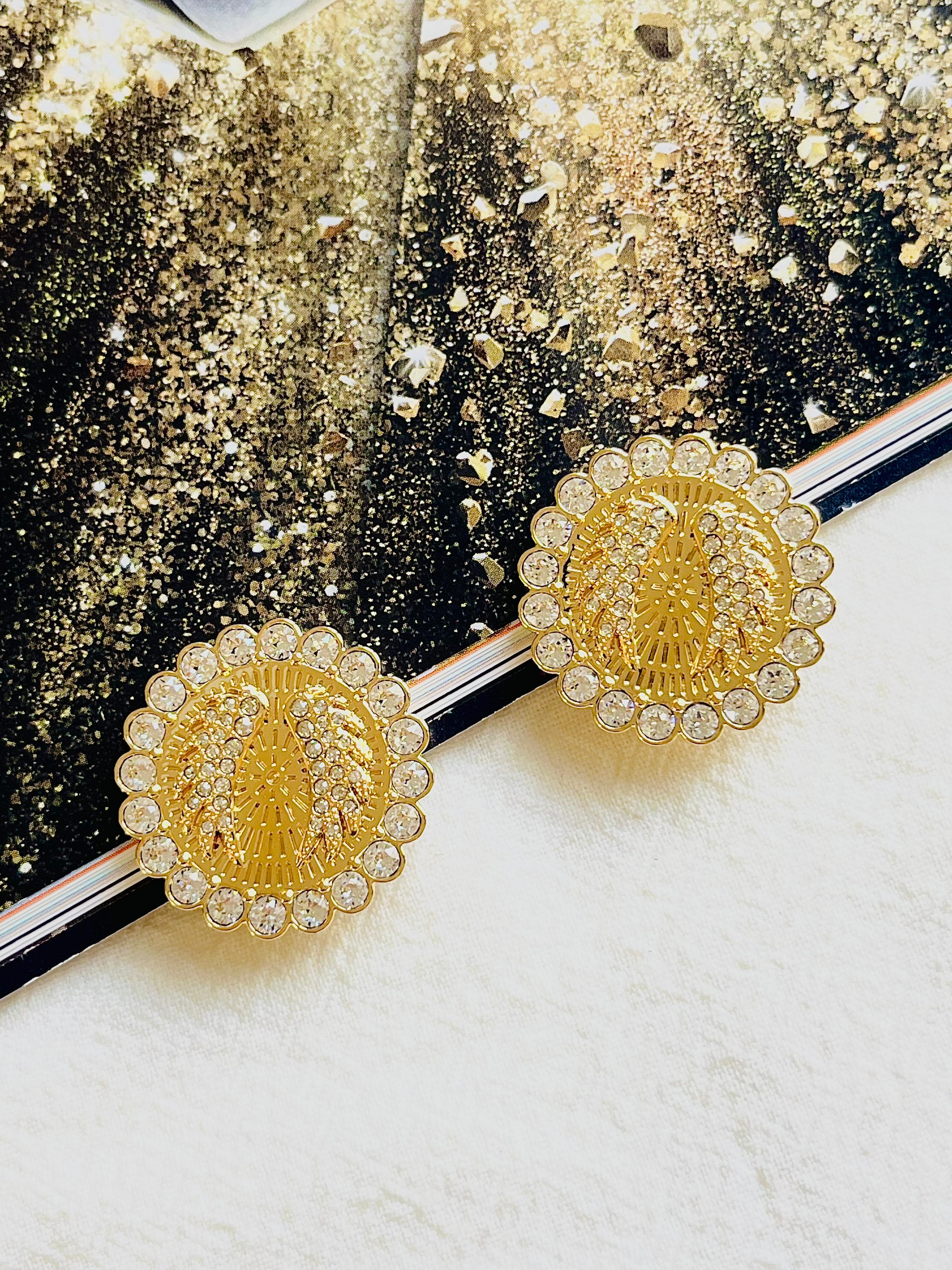 Dieses Paar Clip-Ohrringe in Maxigröße aus schimmerndem, klarem Pavé und fein verarbeitetem, vergoldetem Metall verleiht Ihrem Ensemble einen Hauch von bedeutungsvollem Glamour. Jede Scheibenform ist mit einem Paar Engelsflügeln verziert, einem