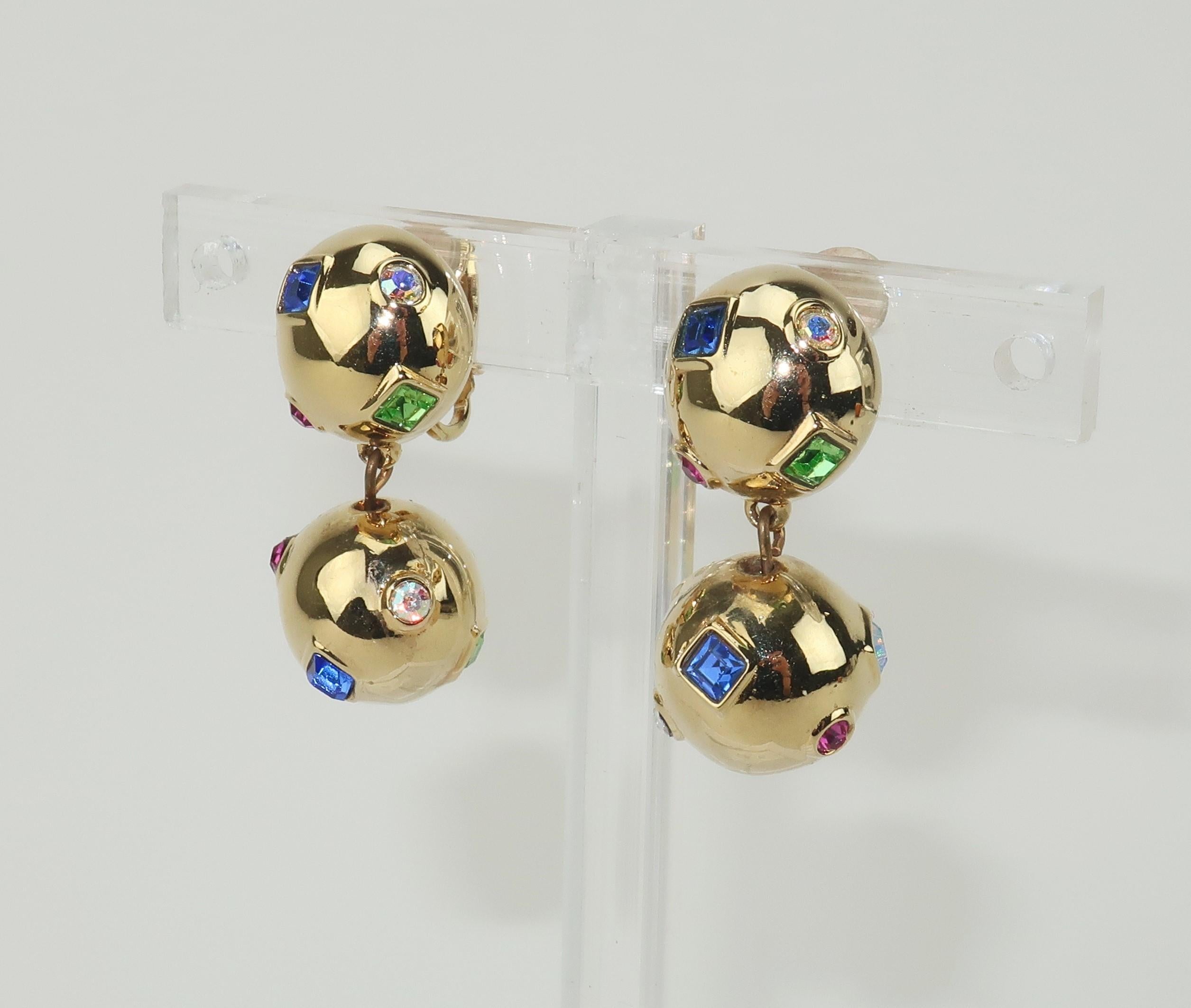 A beautiful pair of gold tone dangle orb earrings embellished with Swarovski sparkling crystal rhinestones in multi color shades of ruby red, sapphire blue, peridot green and iridescent pink.  Outfitted with clip on hardware and signed with the