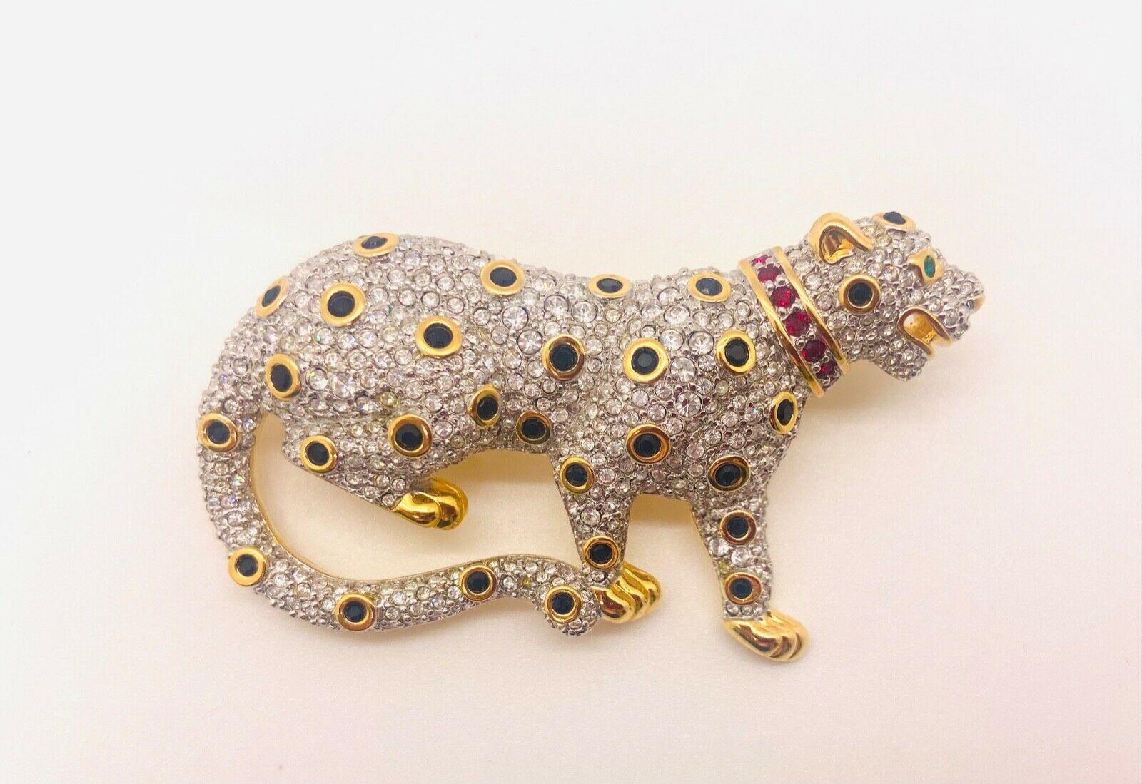 An authentic rare retired Swarovski pave' crystal leopard brooch or pin. The beautiful brooch is engraved with the Swarovski logo in the back and is gold plated featuring clear pave colored crystal accented with green and red crystals through out
