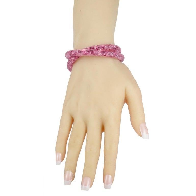 Lending their enticing, sparkling allure to the piece, the lovely pink crystals that fill the intricate pink fishnet tube give a delightfully feminine appeal to this fascinatingly envisioned bracelet. The bracelet is presented by Swarovski for the
