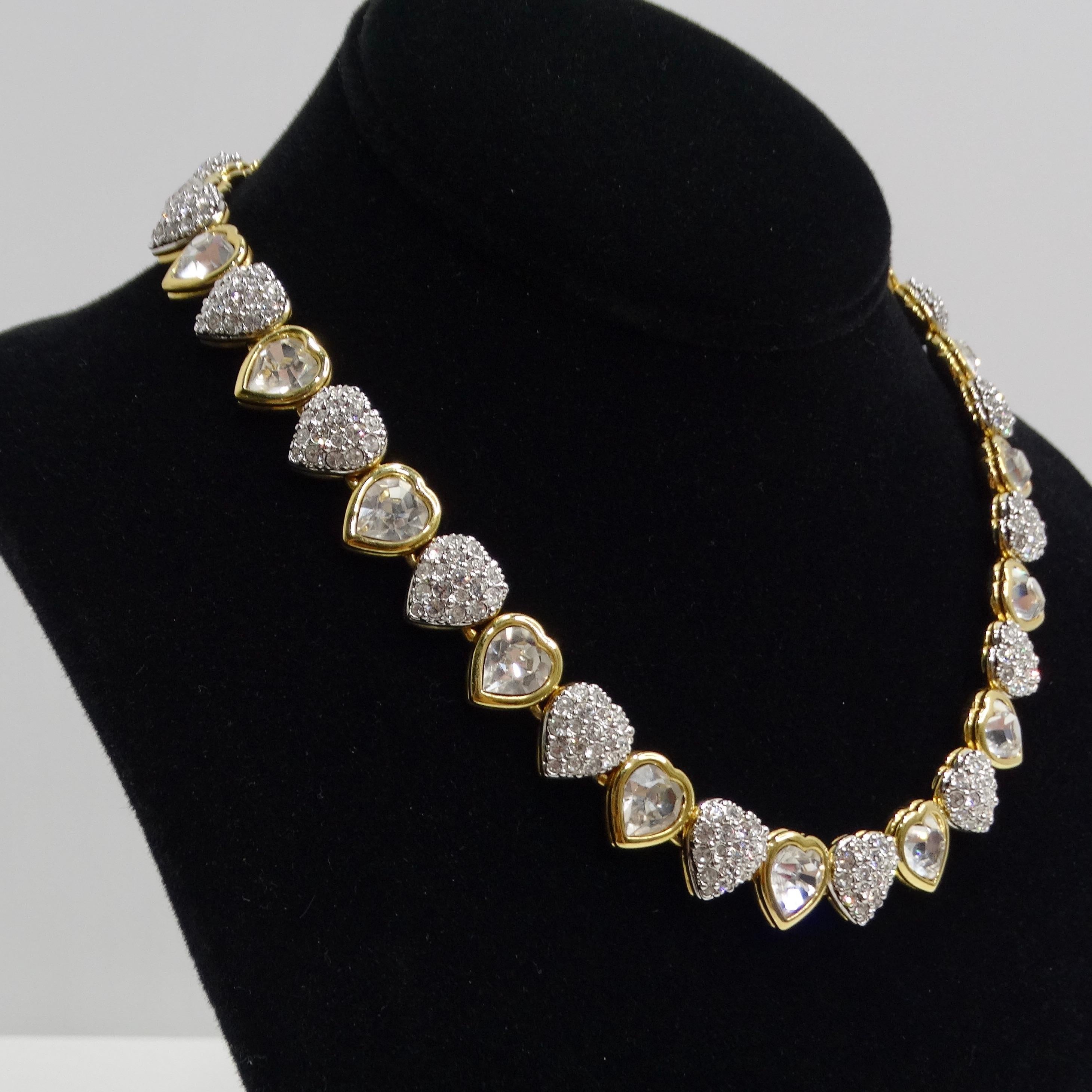The Swarovski Vintage 14K Gold Plated Crystal Heart Choker is a glamorous and eye-catching piece from the 1980s that embodies the elegance and sparkle associated with Swarovski crystals. This choker-style necklace features a series of heart-shaped