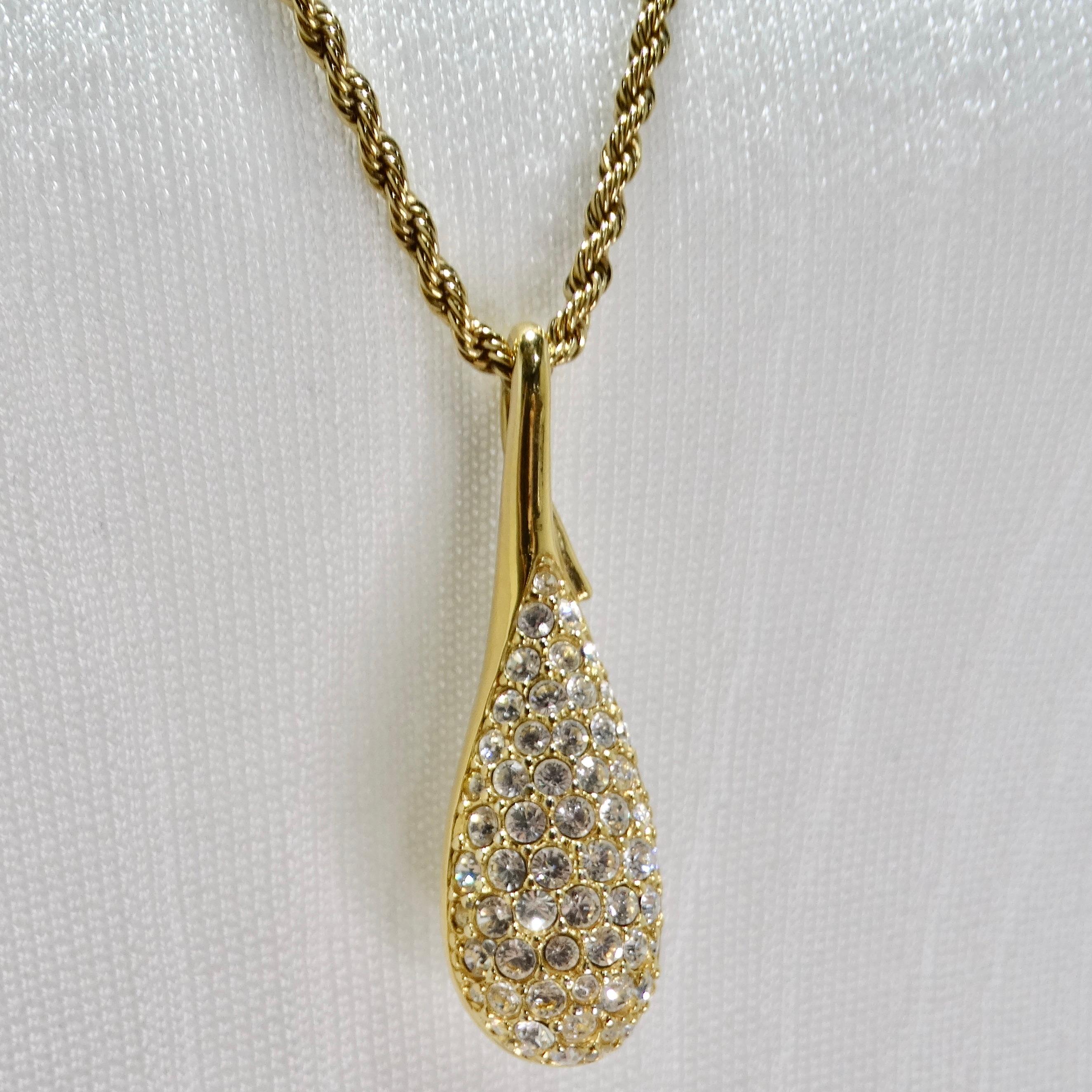 The Swarovski Vintage 18K Gold Plated Crystal Pendant Necklace is a glamorous piece from the 1980s that combines elegance with the brilliance of Swarovski rhinestones. This chain necklace features a large teardrop-shaped pendant adorned with