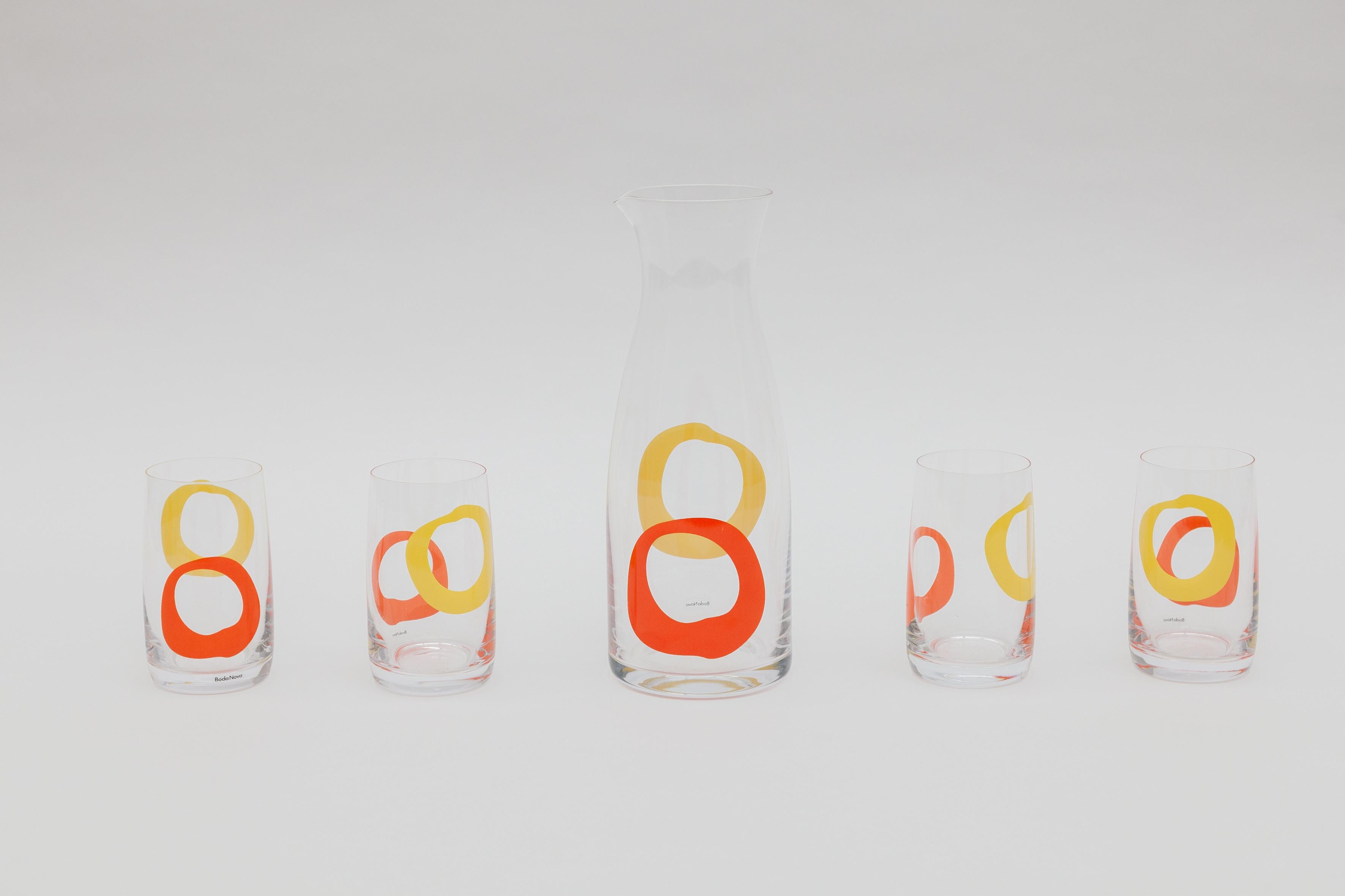 The Boda Nova carafe and four matches longdrinks. The design of the carafe is based on the gentle lines of the tumbler in yellow and orange the carafe narrows at its top to form a neck that is easy to grasp and is equally suited to serving fruit