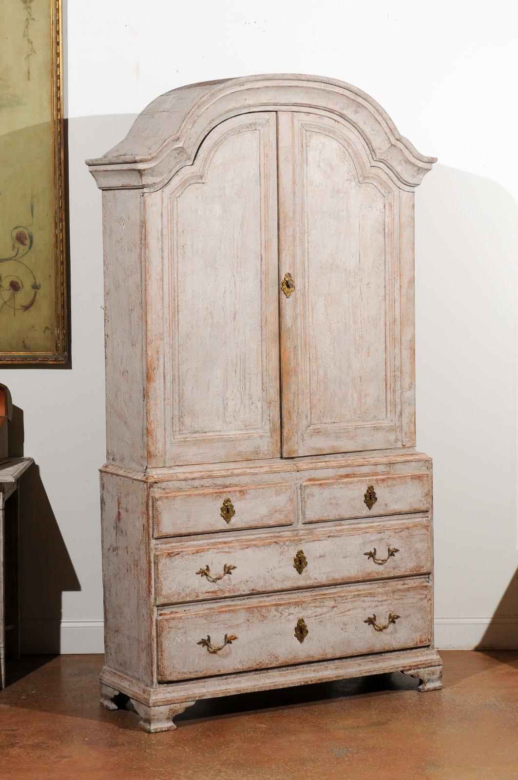 A Swedish Rococo period painted wood cupboard from the 18th century, with upper cabinet over four drawers. Created in Sweden during the third quarter of the 18th century, this painted cupboard features a bonnet cornice sitting above two arching
