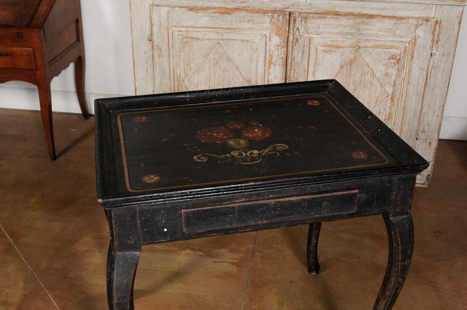 A Swedish Rococo period ebonized wood tea table from the late 18th century, with painted floral décor and cabriole legs. Born in Sweden during the third quarter of the 18th century, this Rococo tea table features a tray top adorned in its center