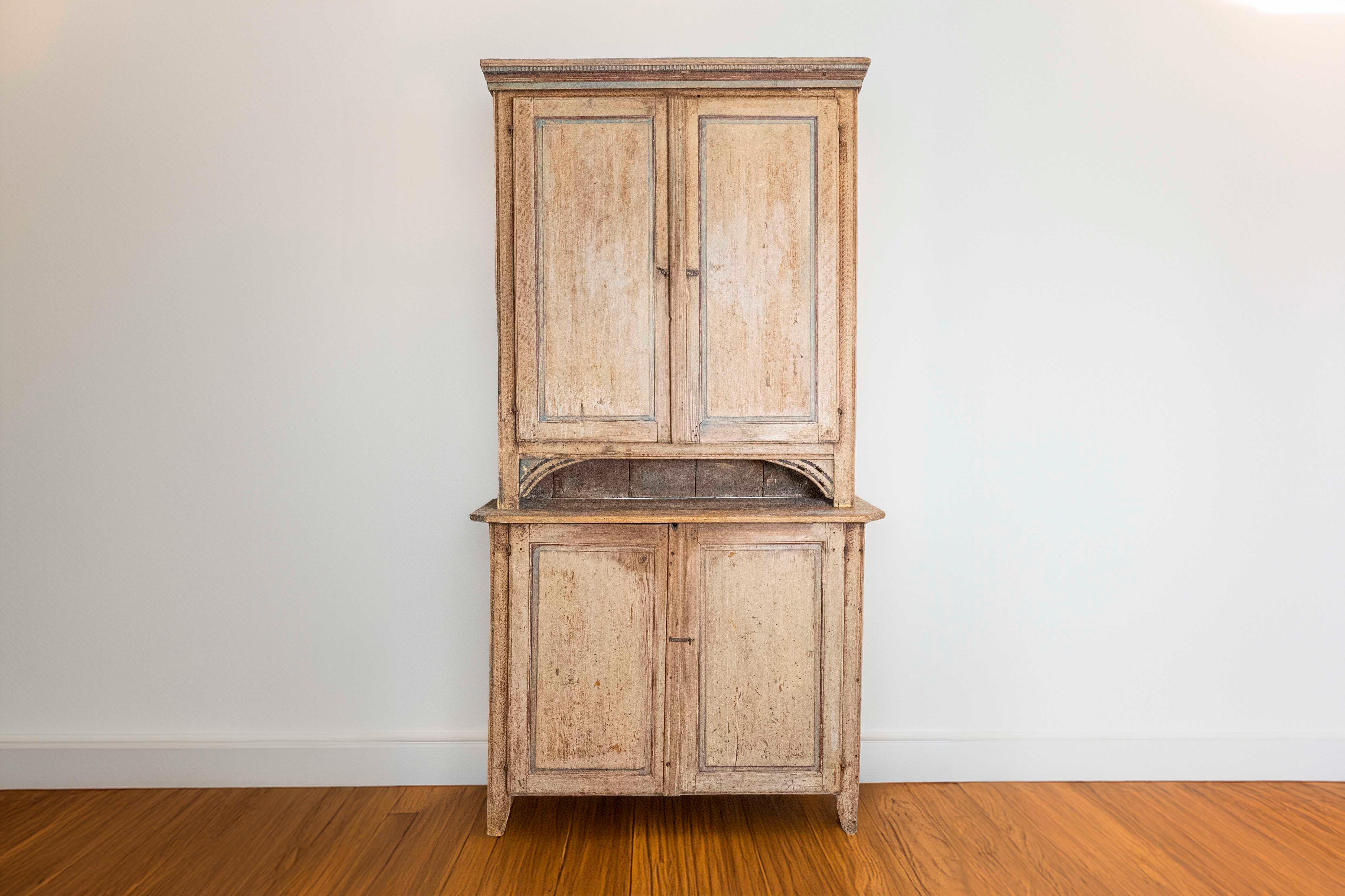 Zweiteiliger schwedischer Holzschrank aus dem späten 18. Jahrhundert, mit Originallackierung, geschnitzten Akzenten, Zinnenleiste, vier Türen und Patina. Dieser im letzten Viertel des 18. Jahrhunderts in Schweden gefertigte Holzschrank weist ein