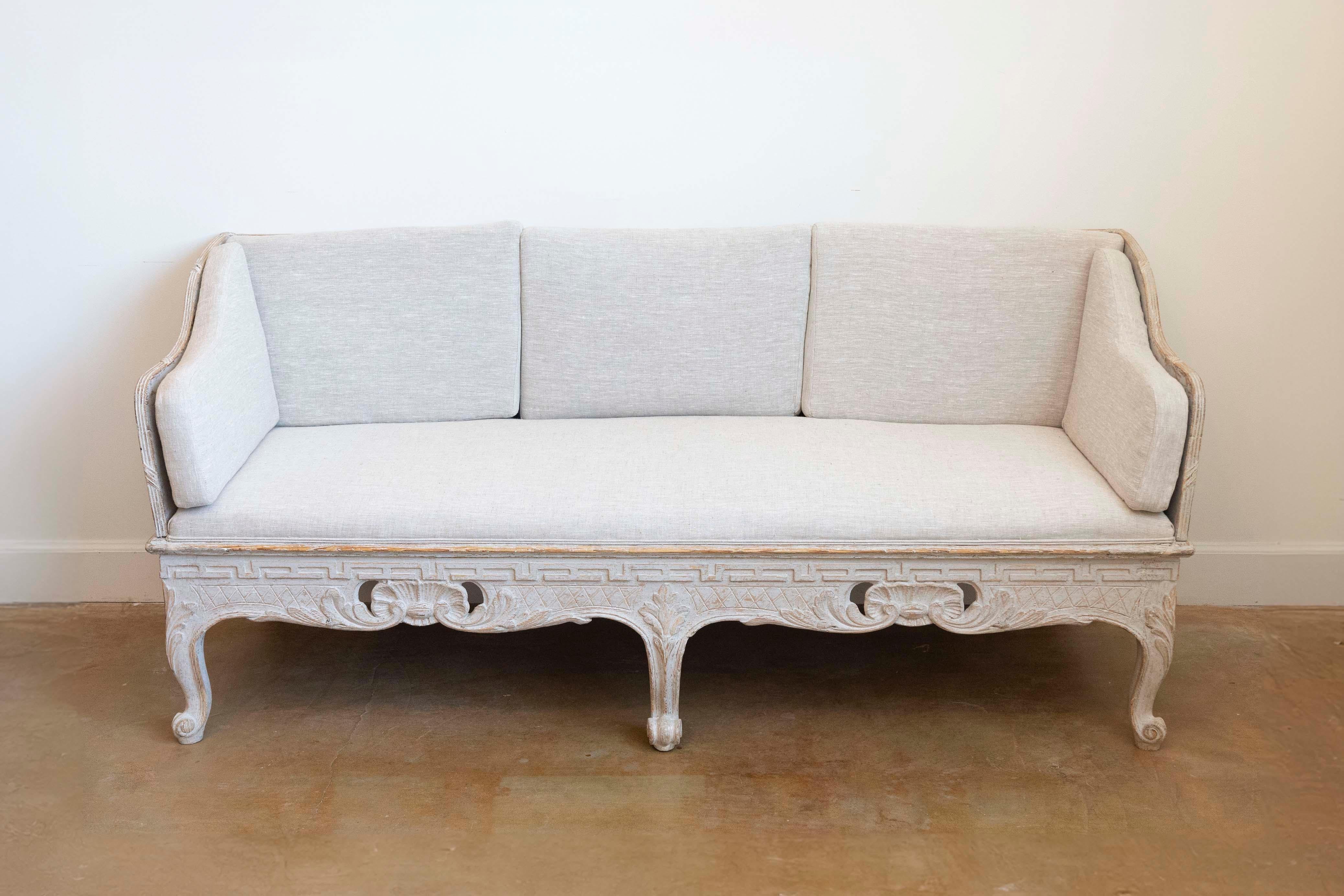 A Swedish Rococo period painted wood Trågsoffa from the late 18th century, with upholstered seat, shell carved apron, meander motifs and cabriole legs. Created in Sweden during the last quarter of the 18th century, this Rococo period Trågsoffa