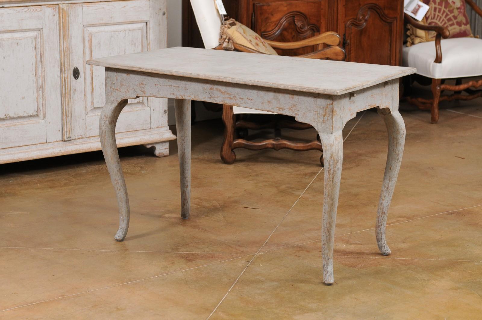 A Swedish Rococo period table from the late 18th century, with cabriole legs and distressed finish. Created in Sweden during the last quarter of the 18th century, this table features a rectangular top sitting above four cabriole legs. Painted in a