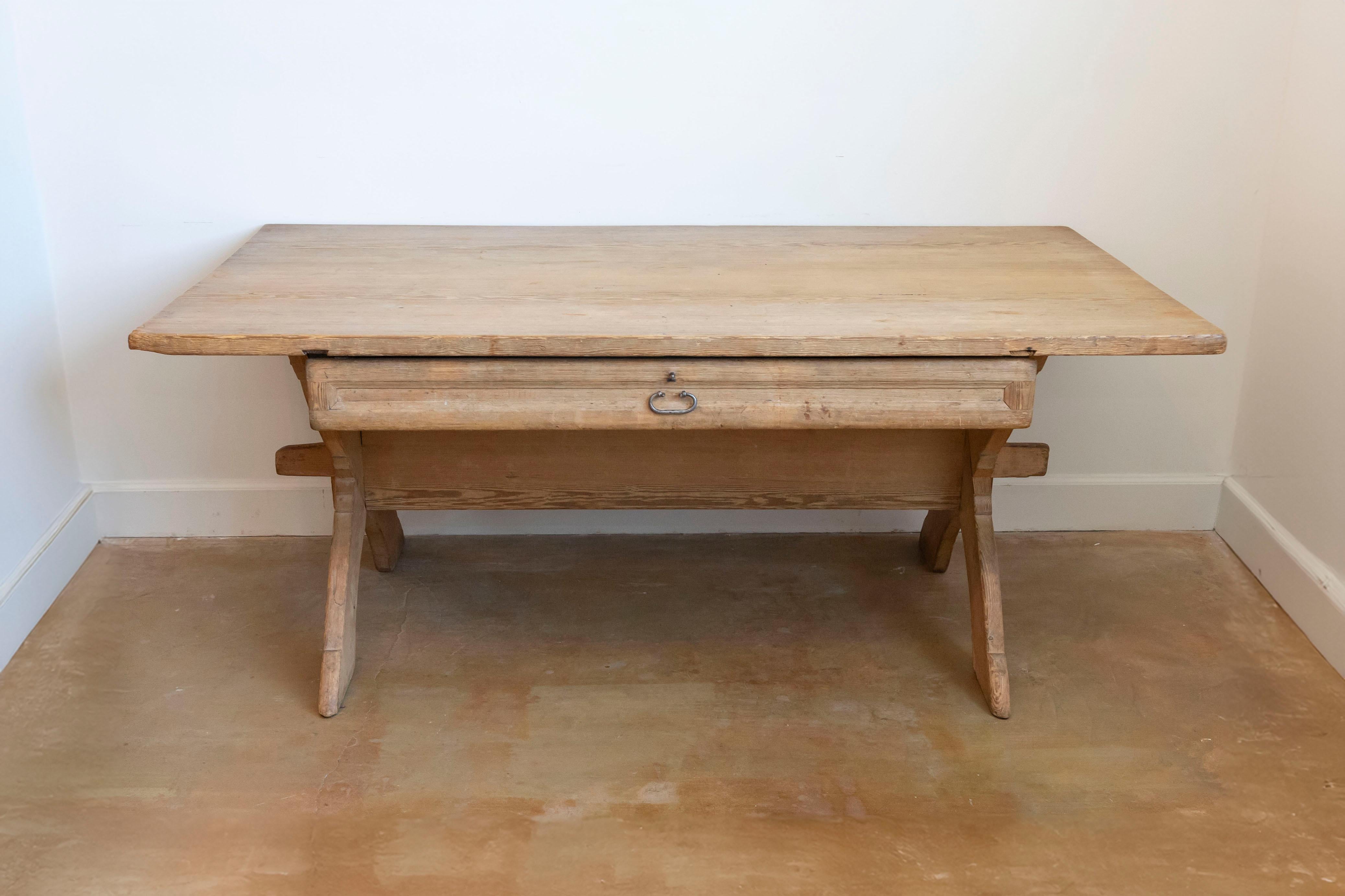 A rustic Swedish European pine sawbuck trestle table circa 1790 with double X-Form base, long drawer and weathered patina. Embrace the beauty of rustic simplicity with this charming Swedish European pine sawbuck trestle table from the late 18th