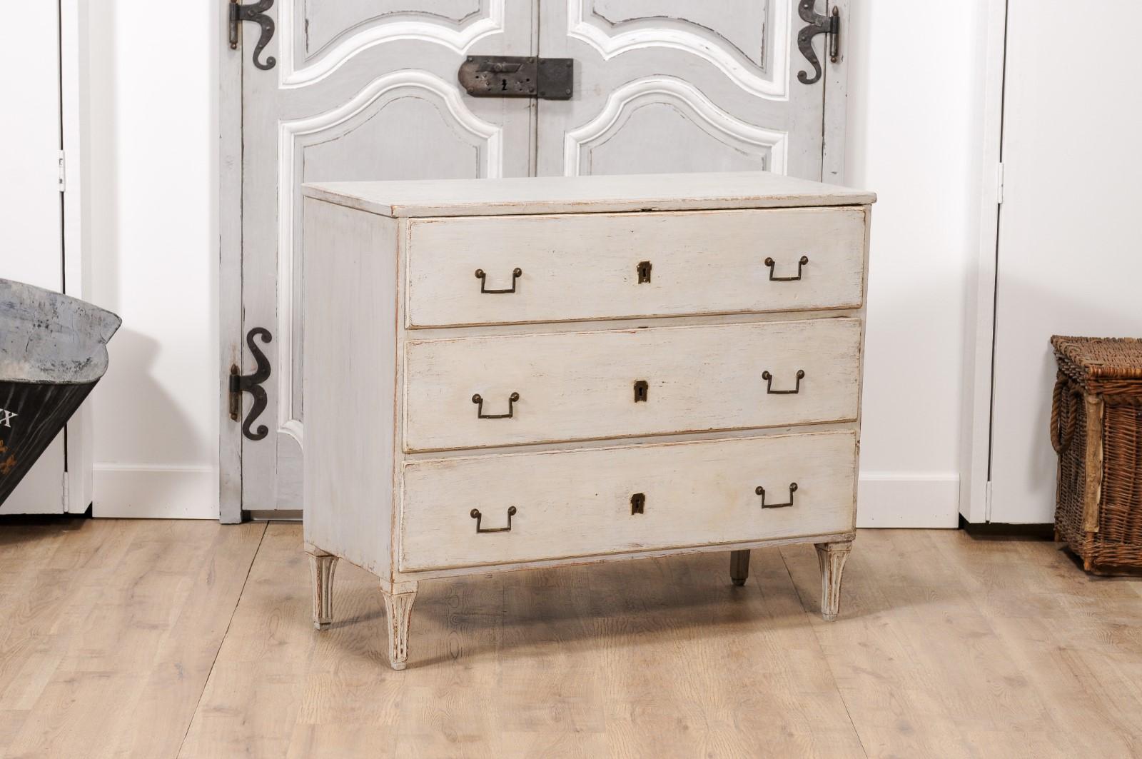 A Swedish Gustavian period painted wood chest from circa 1790 with three drawers, linear hardware and carved fluted feet. Embodying the refined simplicity of the Swedish Gustavian era, this painted wood chest from circa 1790 offers a serene and