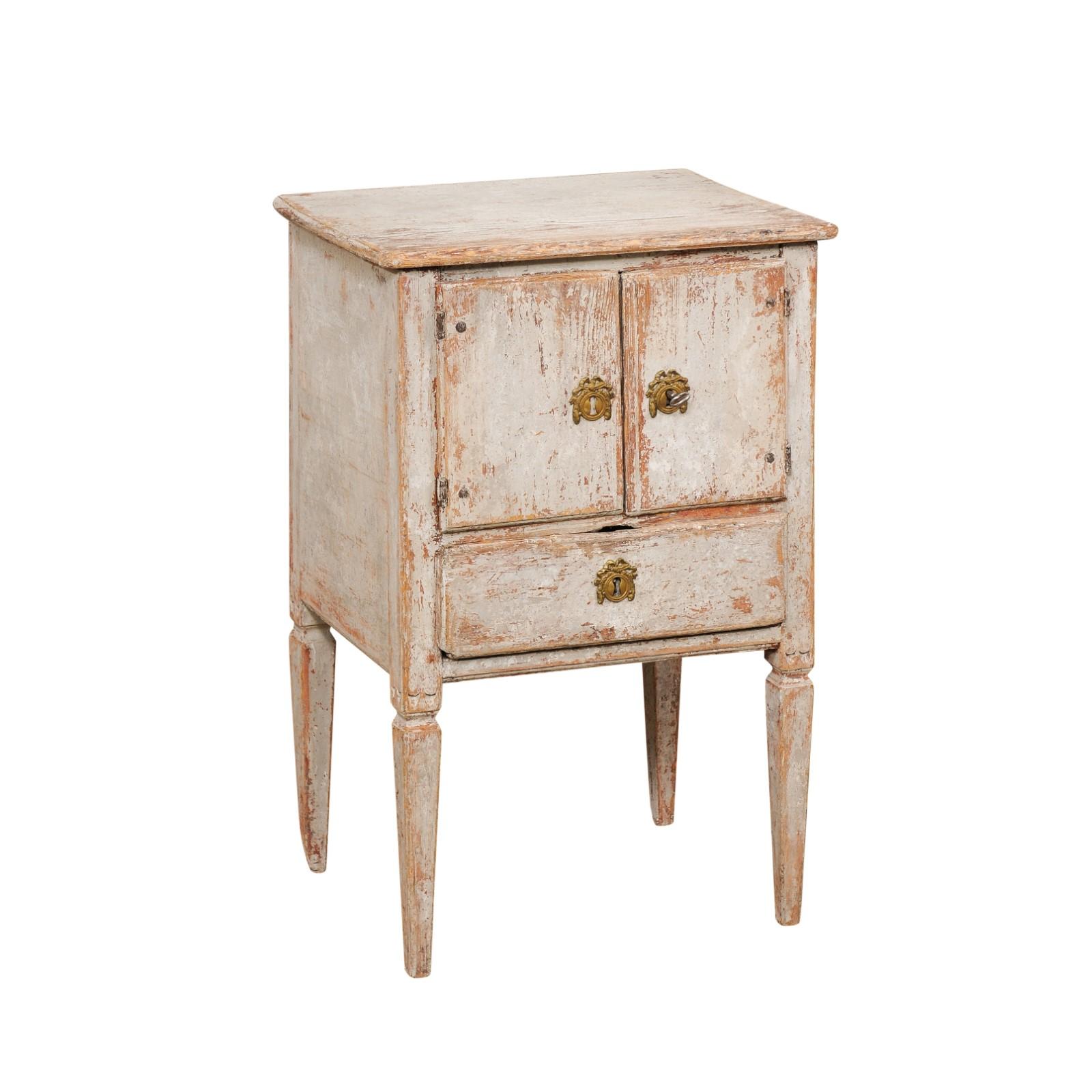 A Swedish Gustavian period painted wood nightstand table from the late 18th century, with a pair of petite double doors, a single drawer and distressed patina. Created in Sweden during the last decade of the 18th century, this painted bedside table