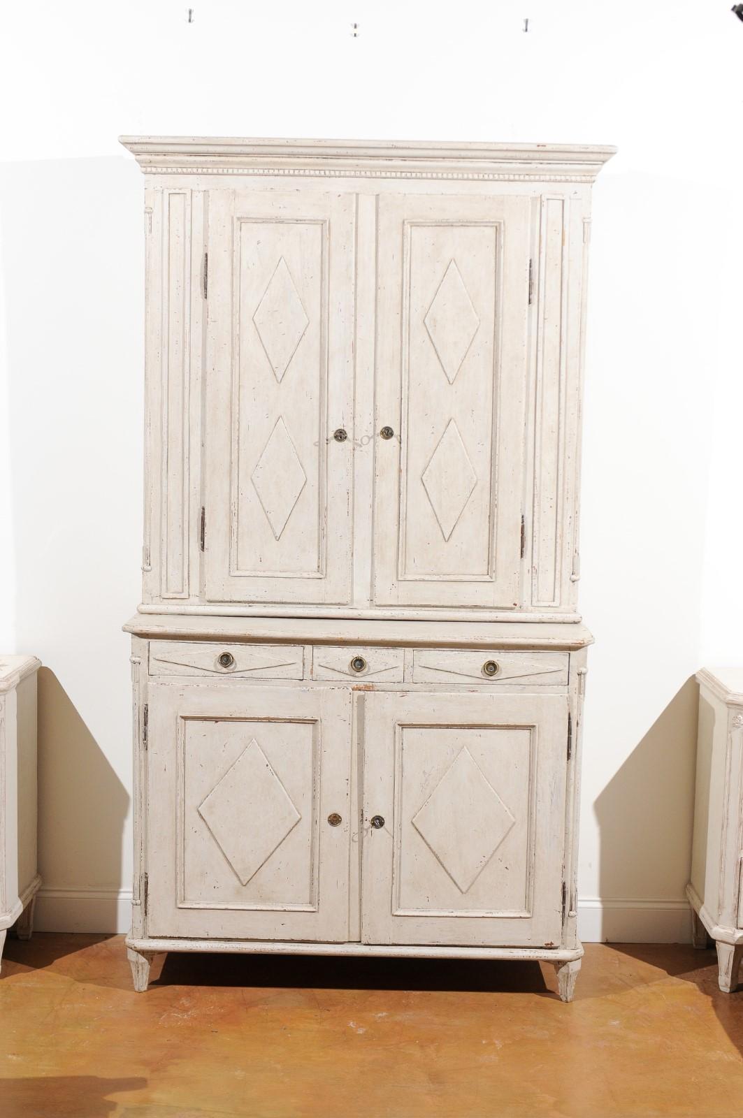 A Swedish Gustavian period two-part tall painted wood cabinet from the late 18th century, with doors, drawers and diamond motifs. Born in Sweden at the end of the 18th century, this elegant cabinet features a molded cornice with reeded accents,