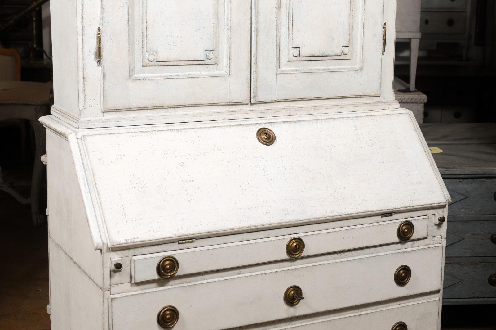 A Swedish Gustavian period two-part secretary from the late 18th century, with carved cornice and slanted front desk. Created in Sweden during the last decade of the 18th century, this Gustavian painted wood tall secretary features a carved cornice