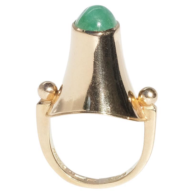 This 18 karat gold ring is adorned with a gallery shaped as a golden cone, which is holding a cabochon cut emerald. The shoulders of the ring are shaped as globes and the shank changes shape in a subtle and elegant way.

This ring is a rare item.
