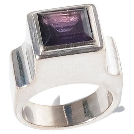 This white gold ring is adorned with a faceted, rectangular amethyst which is framed like a painting. The shank of the ring is quite wide to begin with and from the side you can see how it beautifully widens along its way up to the shoulders and the