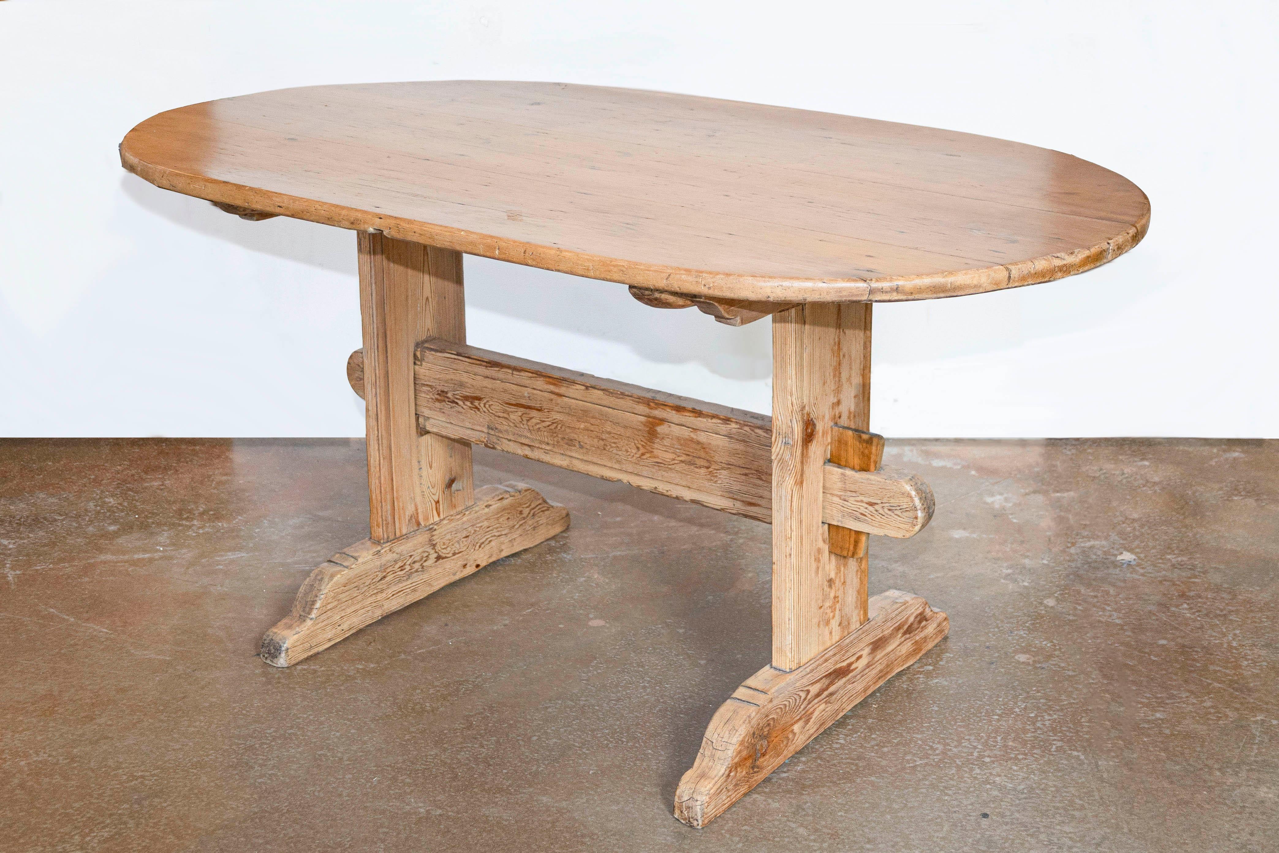 A Swedish Gustavian period rustic dining room table from the early 19th century, with oval top, trestle base and distressed patina. Created in Sweden during the early years of the 19h century, this Gustavian period dining room table charms us with
