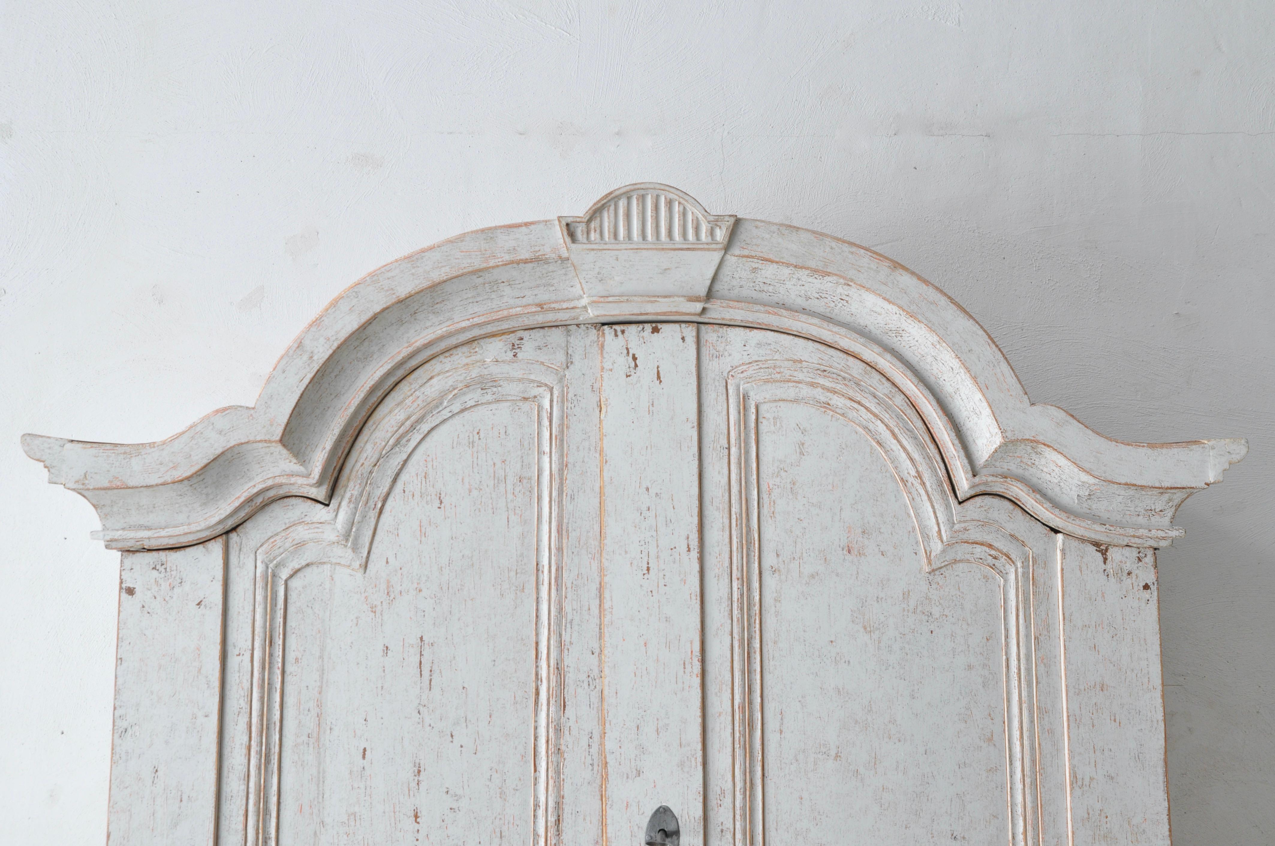 Ein schwedischer großer Sekretär aus Värmland um 1800, grau lackiert, mit geschnitzter Haube, vier Türen, schräger Front und Klammerfüßen. Lassen Sie sich von der schlichten Eleganz des schwedischen gustavianischen Designs mit diesem exquisiten