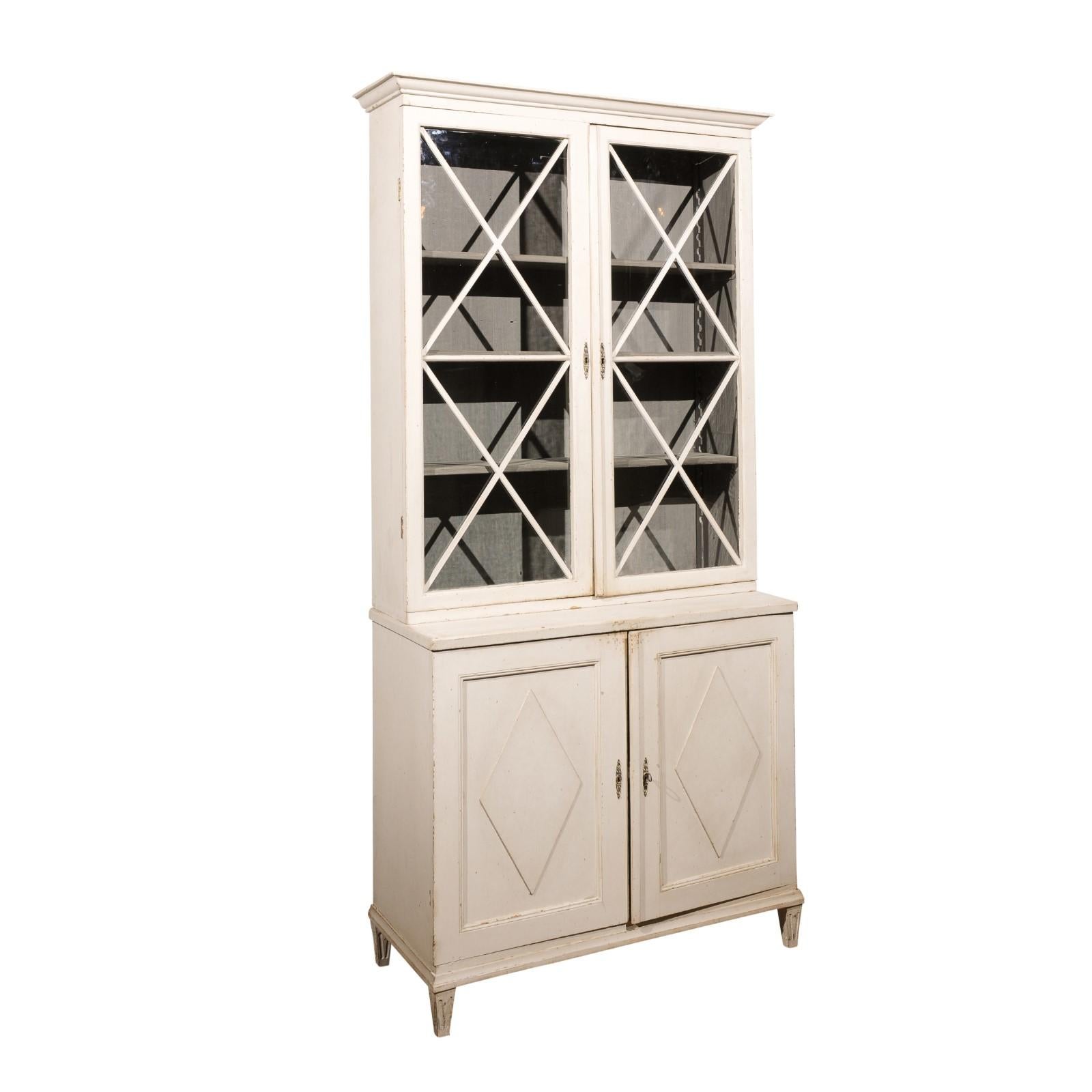 Swedish 19th century two-part vitrine cabinet Circa 1810

A Swedish Gustavian period two-part painted wood vitrine cabinet from the early 19th century, with paneled glass doors and diamond motifs. Created in Sweden during the first quarter of the