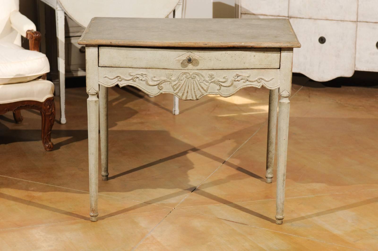 A Swedish Gustavian period painted side table from the early 19th century with single drawer, carved apron and cylindrical legs. Born during the Gustavian era, this Swedish painted side table features a rectangular top with rounded edges, sitting