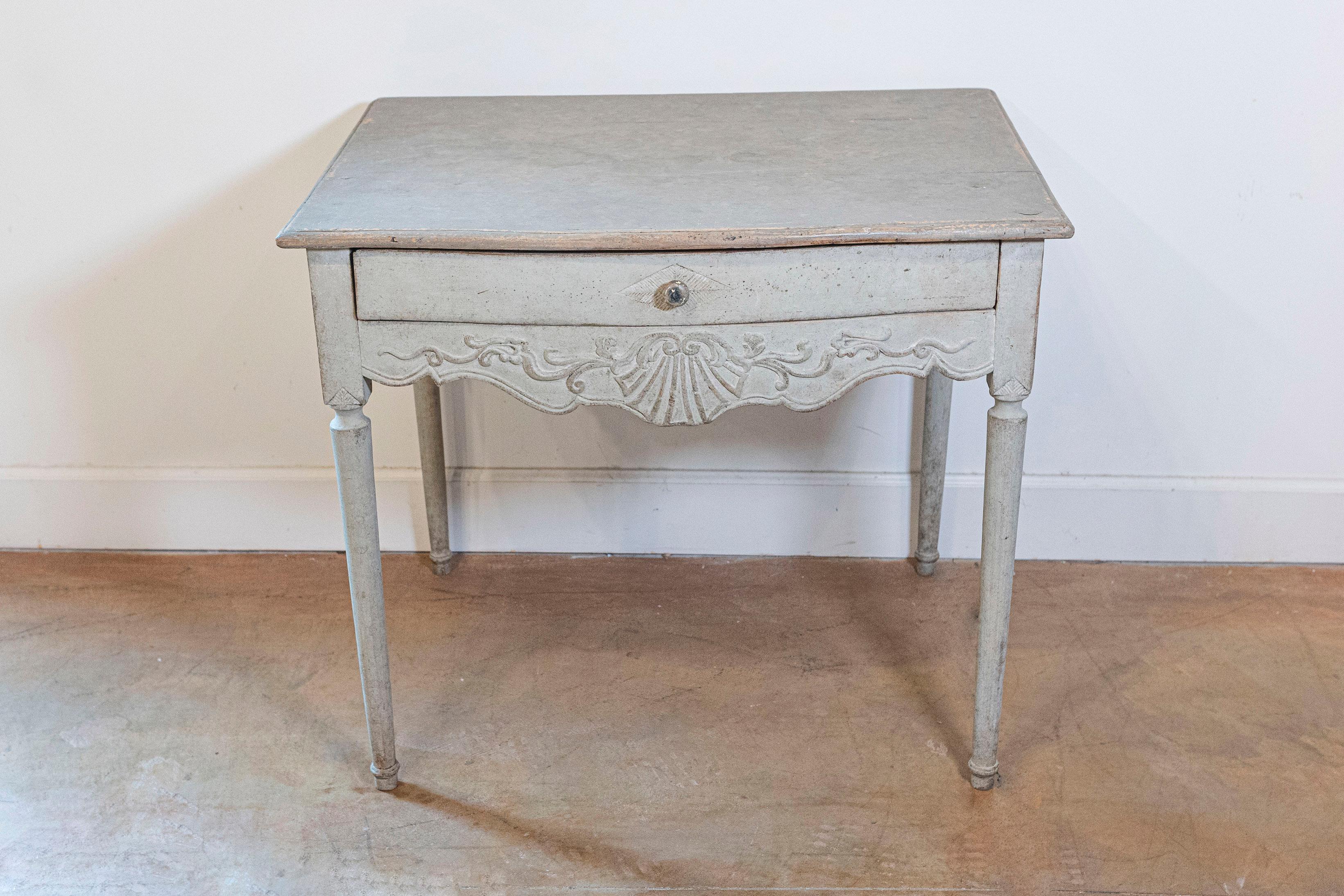 A Swedish Gustavian period painted side table from the early 19th century with single drawer, carved apron and cylindrical legs. Born during the Gustavian era, this Swedish painted side table features a rectangular top with rounded edges, sitting