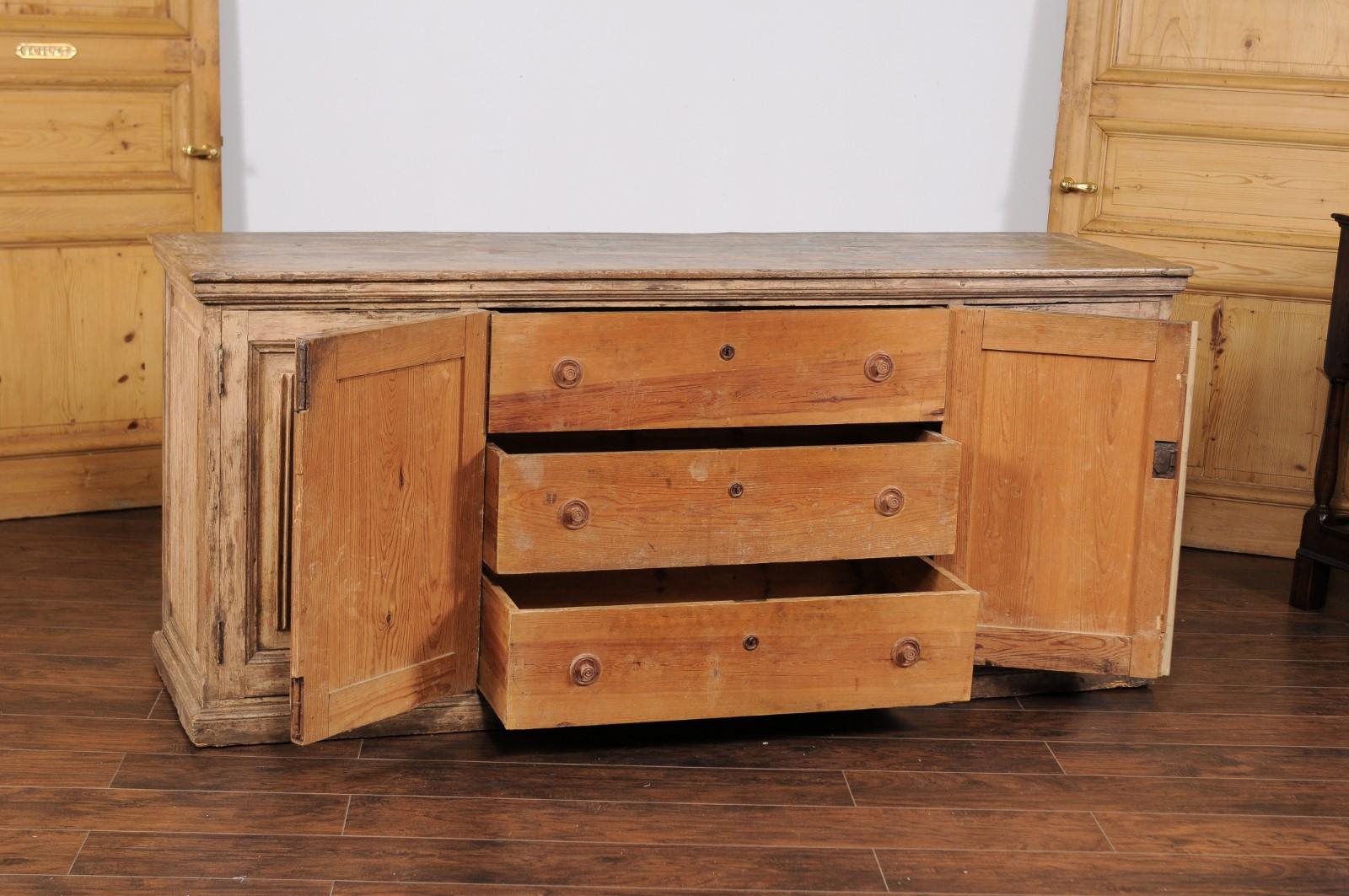 A Swedish pine enfilade from the early 19th century, with four doors, fluted motifs and hidden drawers. Born in Sweden at the end of the Gustavian era, this elegant pine enfilade features a nicely weathered appearance. A rectangular planked top sits