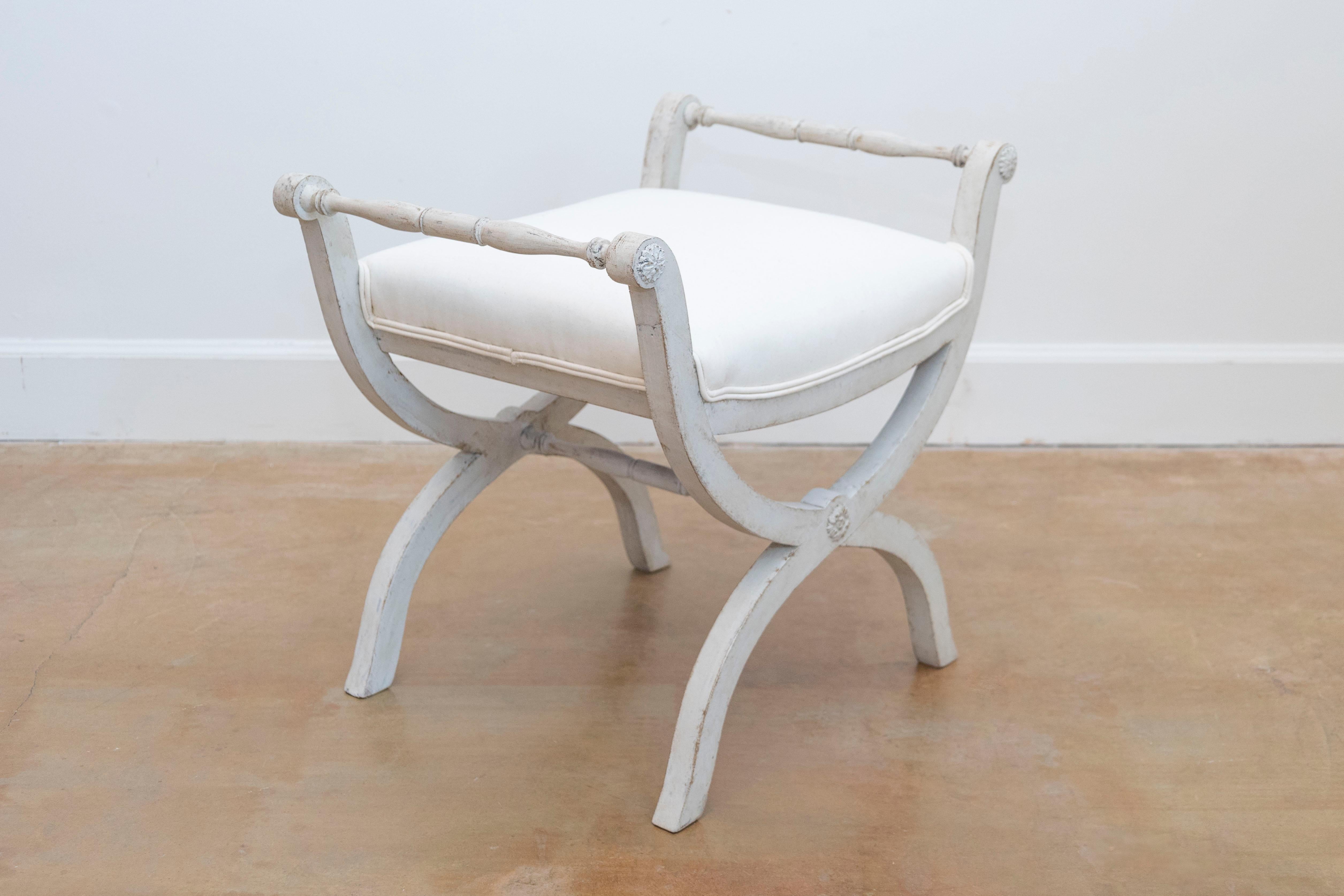 A Swedish Empire style painted wooden Curule stool from the mid-19th century, with spindle arms, X-form base and new upholstery. Created in Sweden during the first half of the 19th century, this stool features a rectangular seat newly recovered with