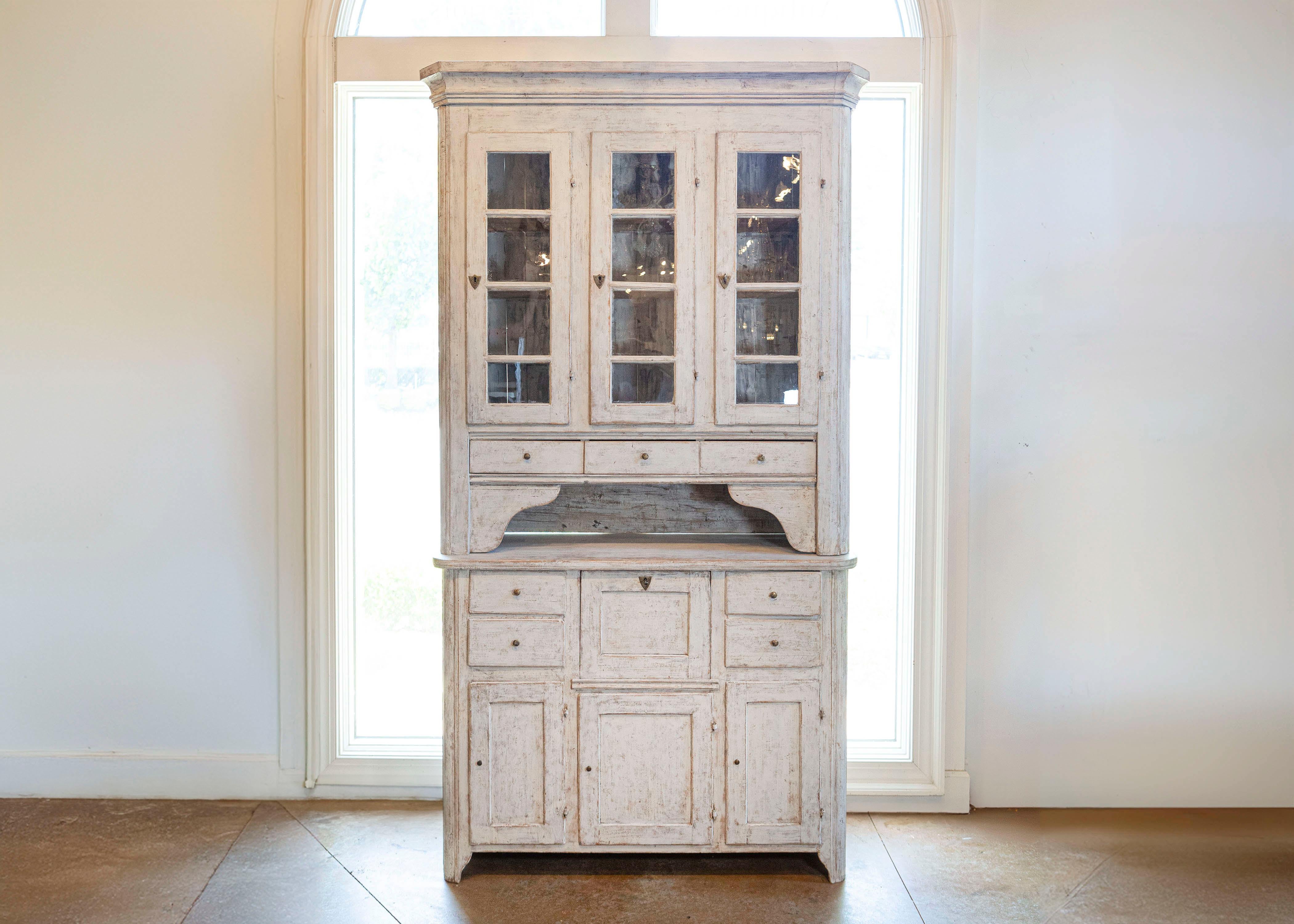 Zweiteiliger schwedischer Vitrinenschrank aus bemaltem Holz aus dem frühen 19. Jahrhundert mit Glastüren, Schubladen und Patina. Diese bemalte Vitrine, die in den frühen Jahren des 19. Jahrhunderts in Schweden hergestellt wurde, zeichnet sich durch