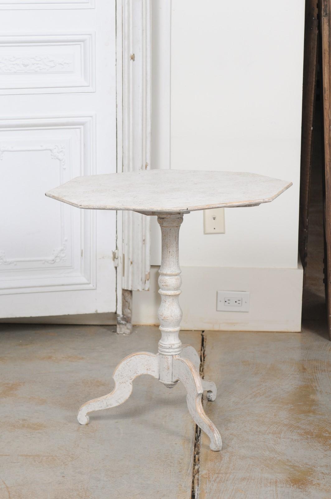 A Swedish painted wood octagonal tilt-top table from the mid-19th century, with turned pedestal base. Created in Sweden during the first half of the 19th century, this painted table features an octagonal tilt-top resting upon a turned pedestal with