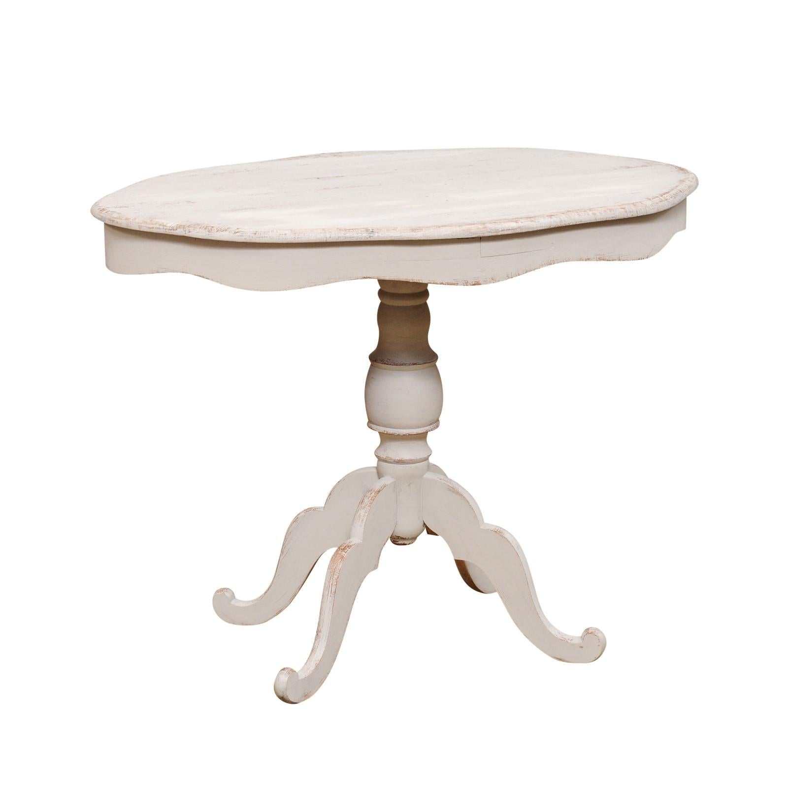 Ein schwedischer, bemalter Holzsockeltisch mit ovaler Platte um 1860 mit geschnitzter, gewellter Schürze, gedrechseltem Sockel und vierbeinigem Fuß. Lassen Sie sich vom skandinavischen Design verführen mit diesem charmanten ovalen Sockeltisch aus
