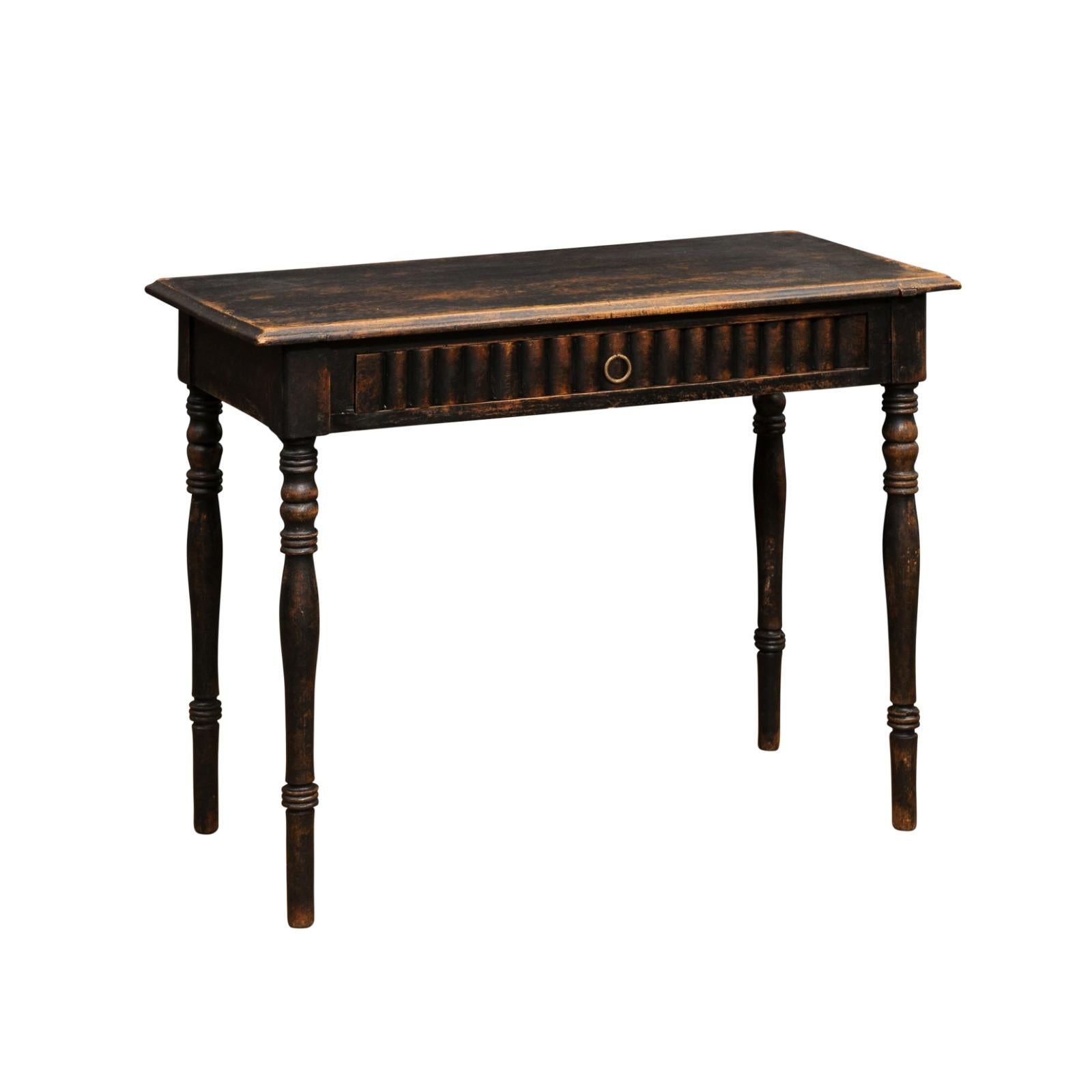 A Swedish painted wood desk from the mid 19th century, with reeded motifs, turned legs and dark patina. Created in Sweden during the third quarter of the 19th century, this painted desk features a rectangular top with beveled edges, sitting above a