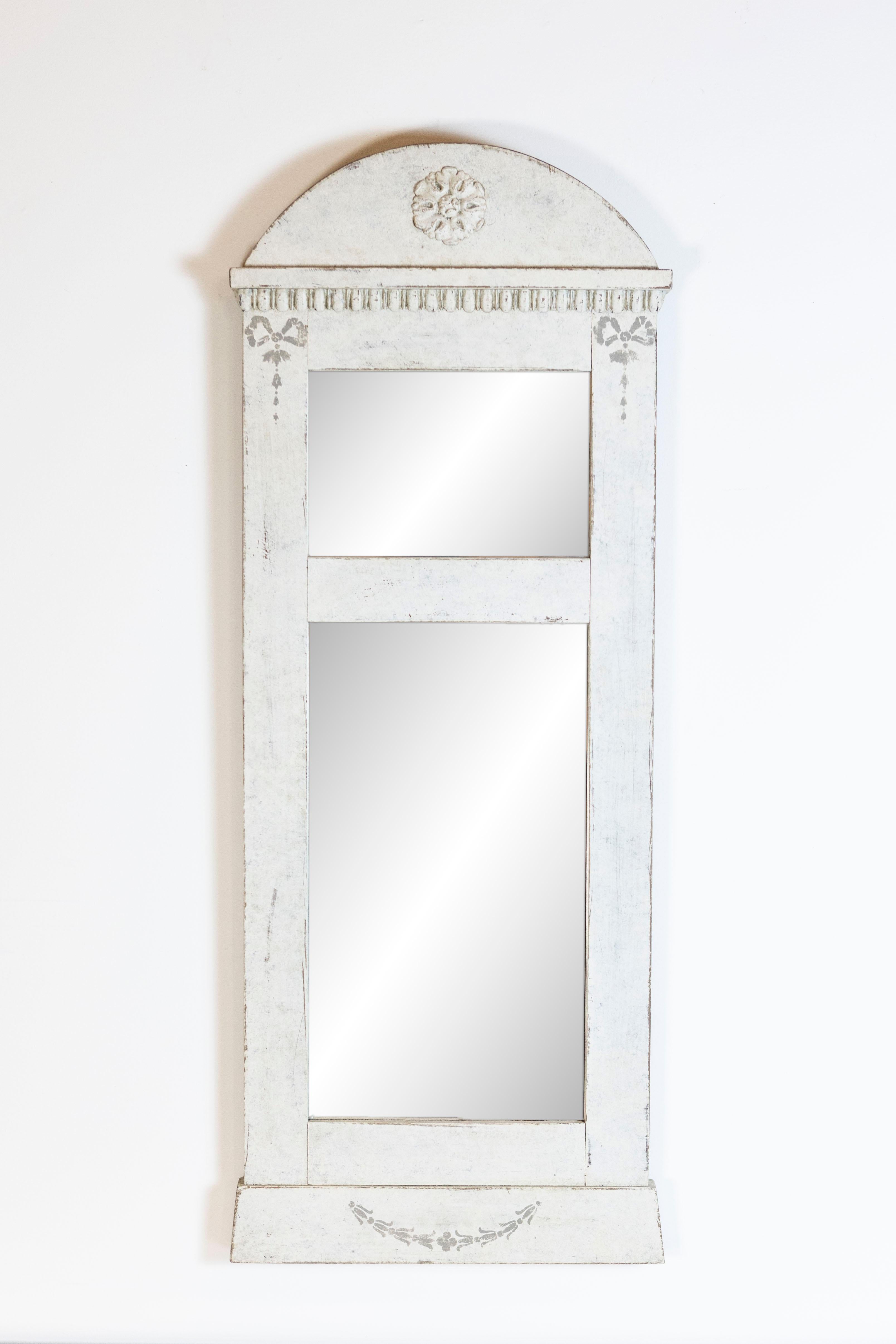 A Swedish mirror from circa 1880 with gray cream painted finish, bonnet top, carved rosette, ribbons and campanulas. This Swedish mirror, dating back to circa 1880, is a remarkable piece that gracefully combines the charm of historic craftsmanship