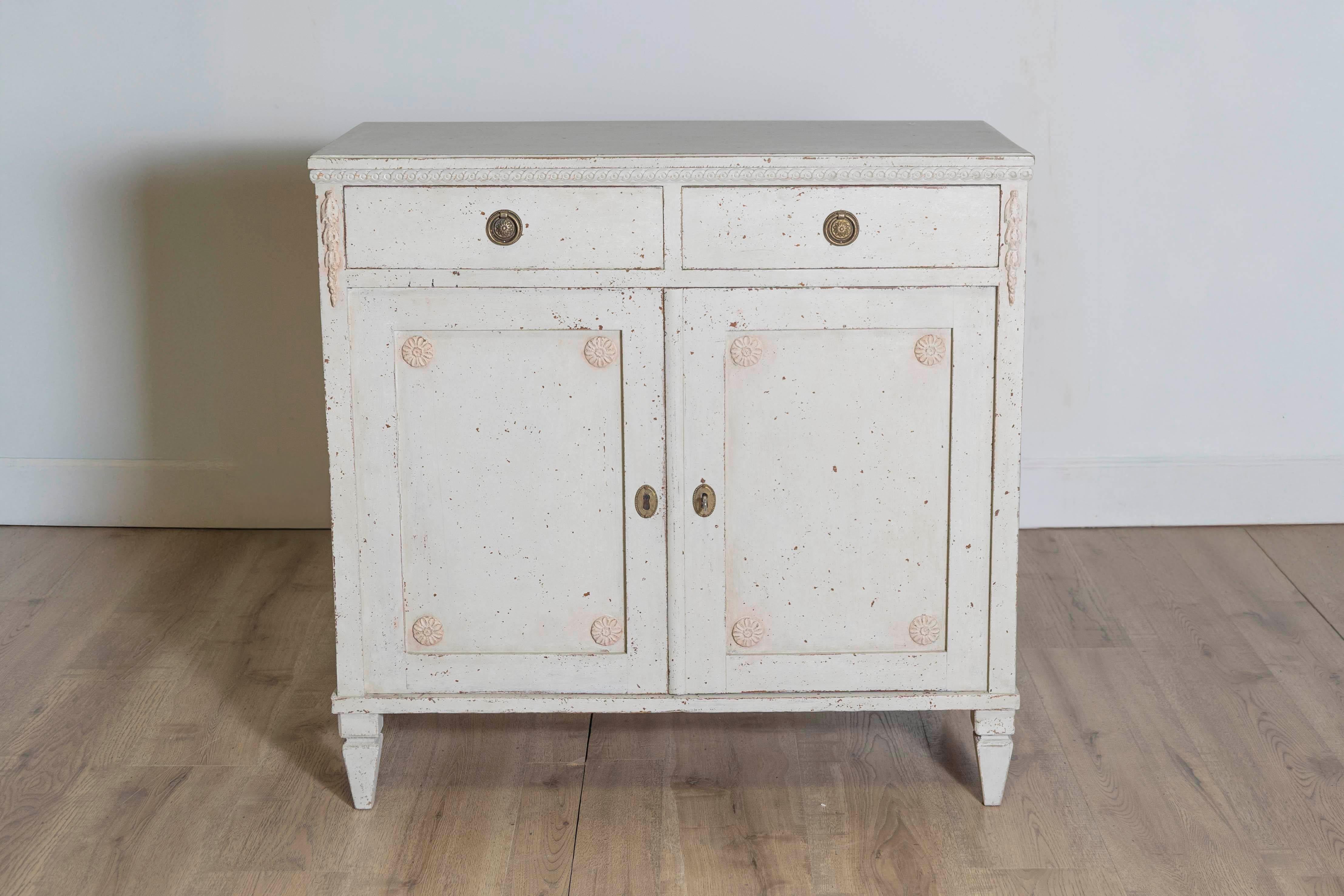 Aparador sueco de estilo Gustaviano pintado de gris, de hacia 1880, con dos puertas, dos cajones, friso guilloché tallado y pequeñas rosetas. Adopta la discreta elegancia del diseño sueco de estilo Gustaviano con este exquisito aparador de hacia