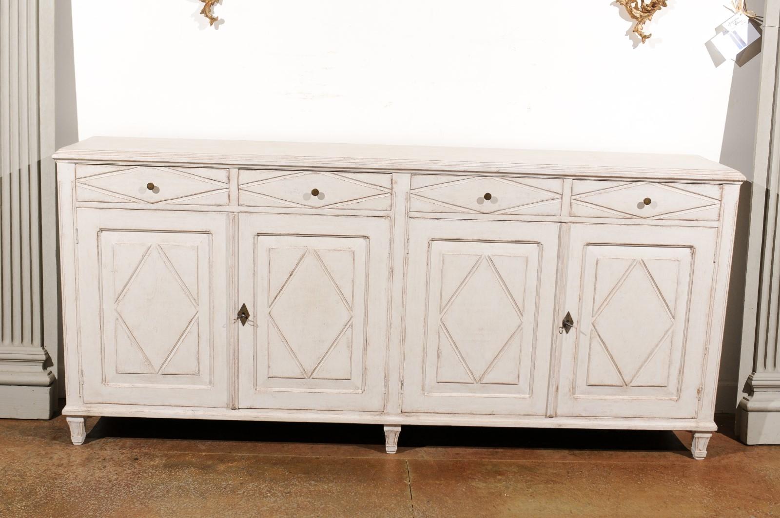 A Swedish Gustavian style painted sideboard from the late 19th century, with four drawers over four doors and diamond motifs. Born in Sweden during the later years of the 19th century, this Swedish enfilade features a rectangular top with molded