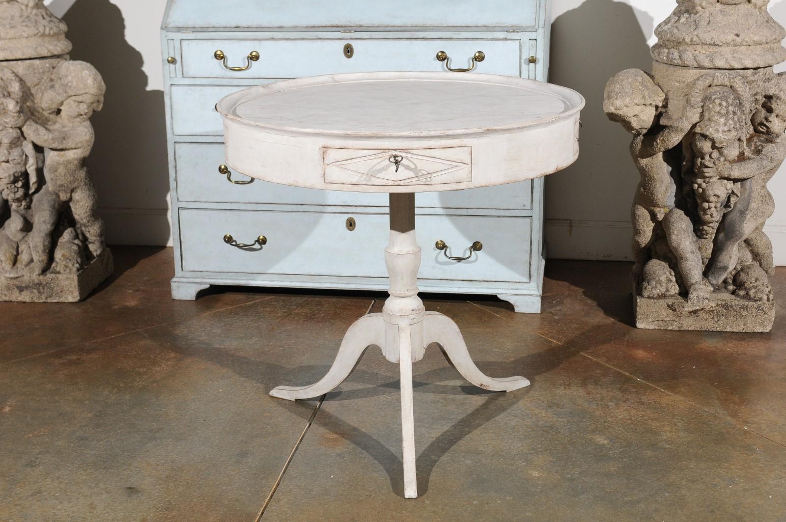 A Swedish painted round pedestal game table from the late 19th century, with marbleized tray top, four drawers and tripod base. Born in Sweden in the last quarter of the 19th century, this elegant side table features a faux-marble painted tray top,