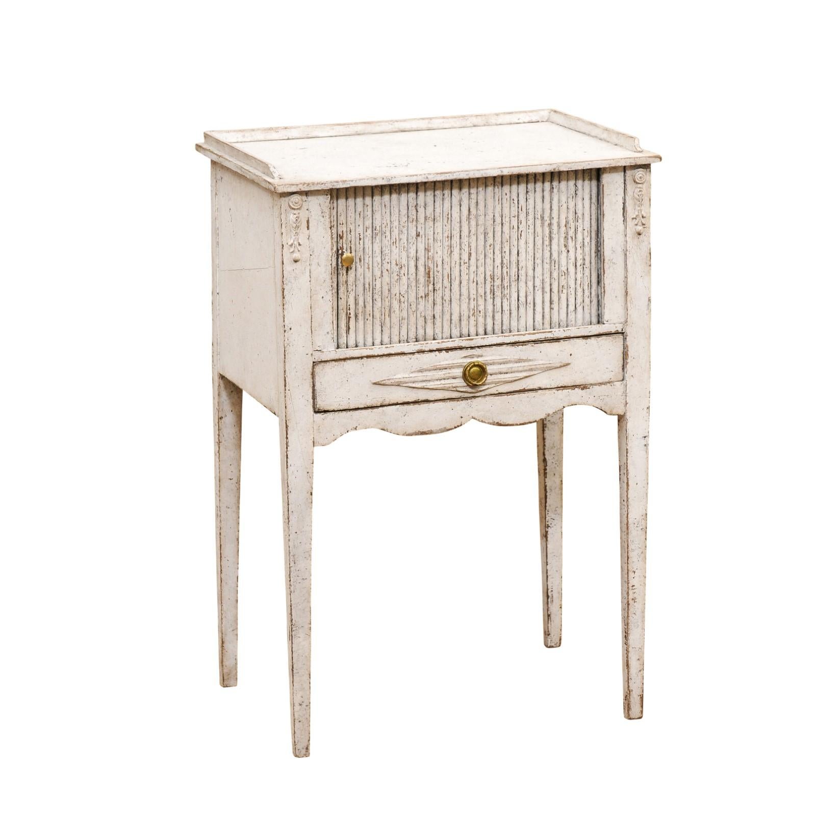 A Swedish painted wood lamp table from the late 19th century with tambour door and distressed patina. Created in Sweden during the last quarter of the 19th century, this lamp table features a rectangular top surrounded by a wooden three quarter